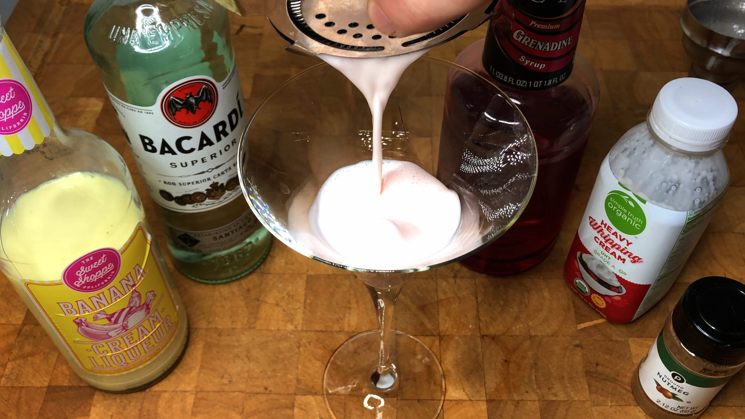 pouring banana cow cocktail into a martini glass
