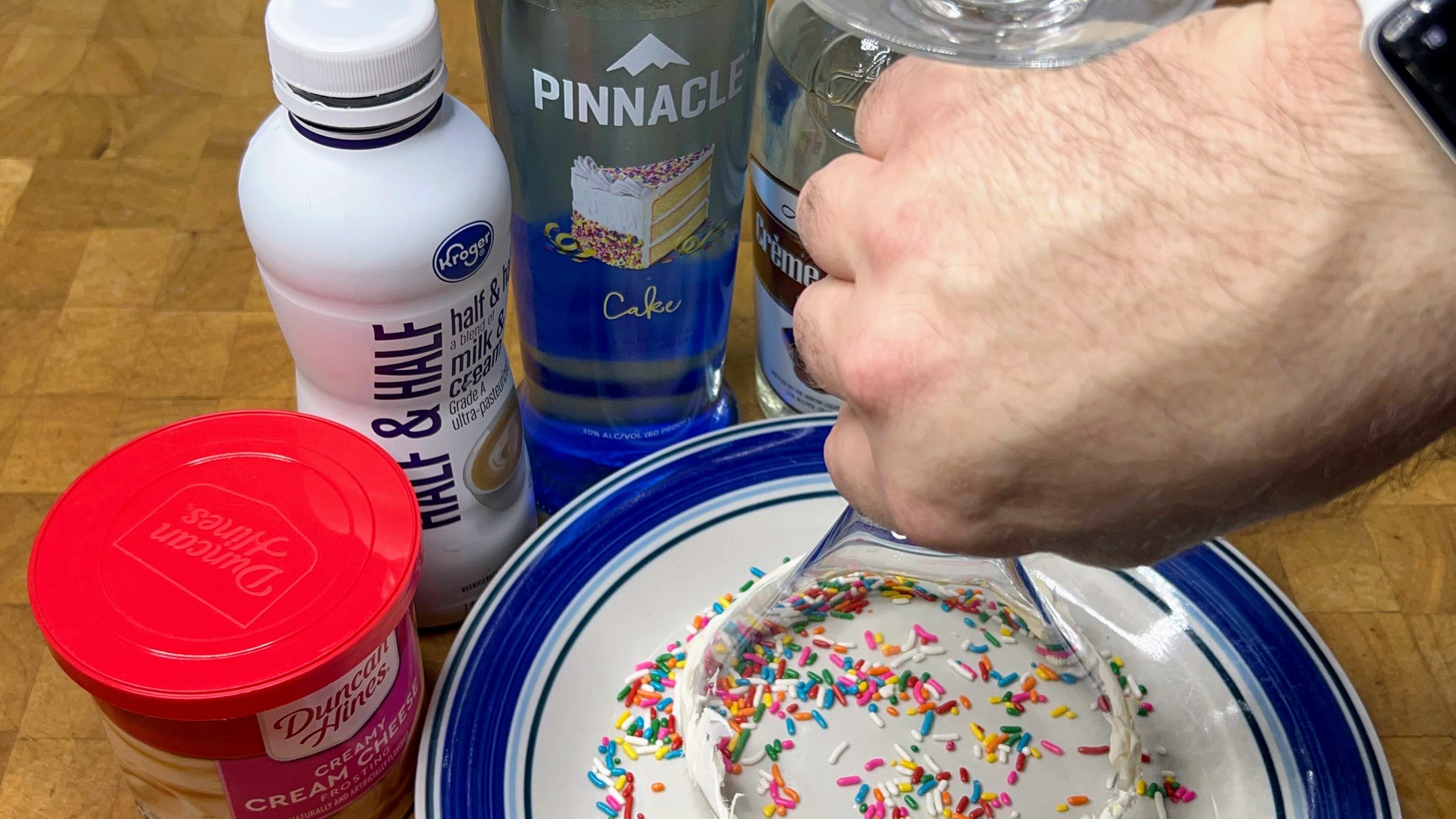 putting sprinkles on the rim of a martini glass that has frosting on it