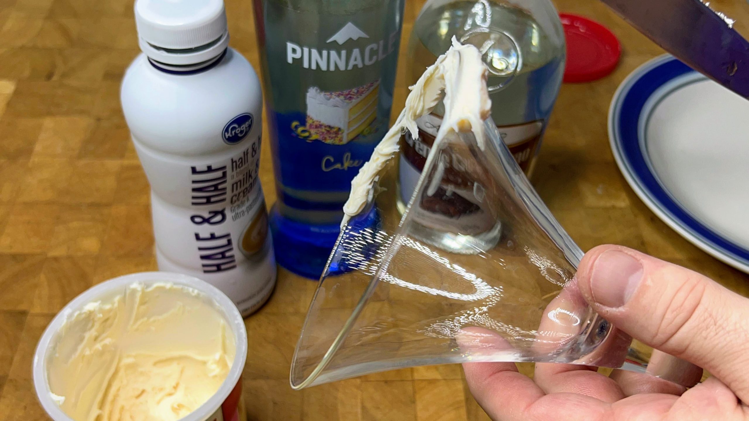 spreading frosting on the rim of a martini glass with a butter knife