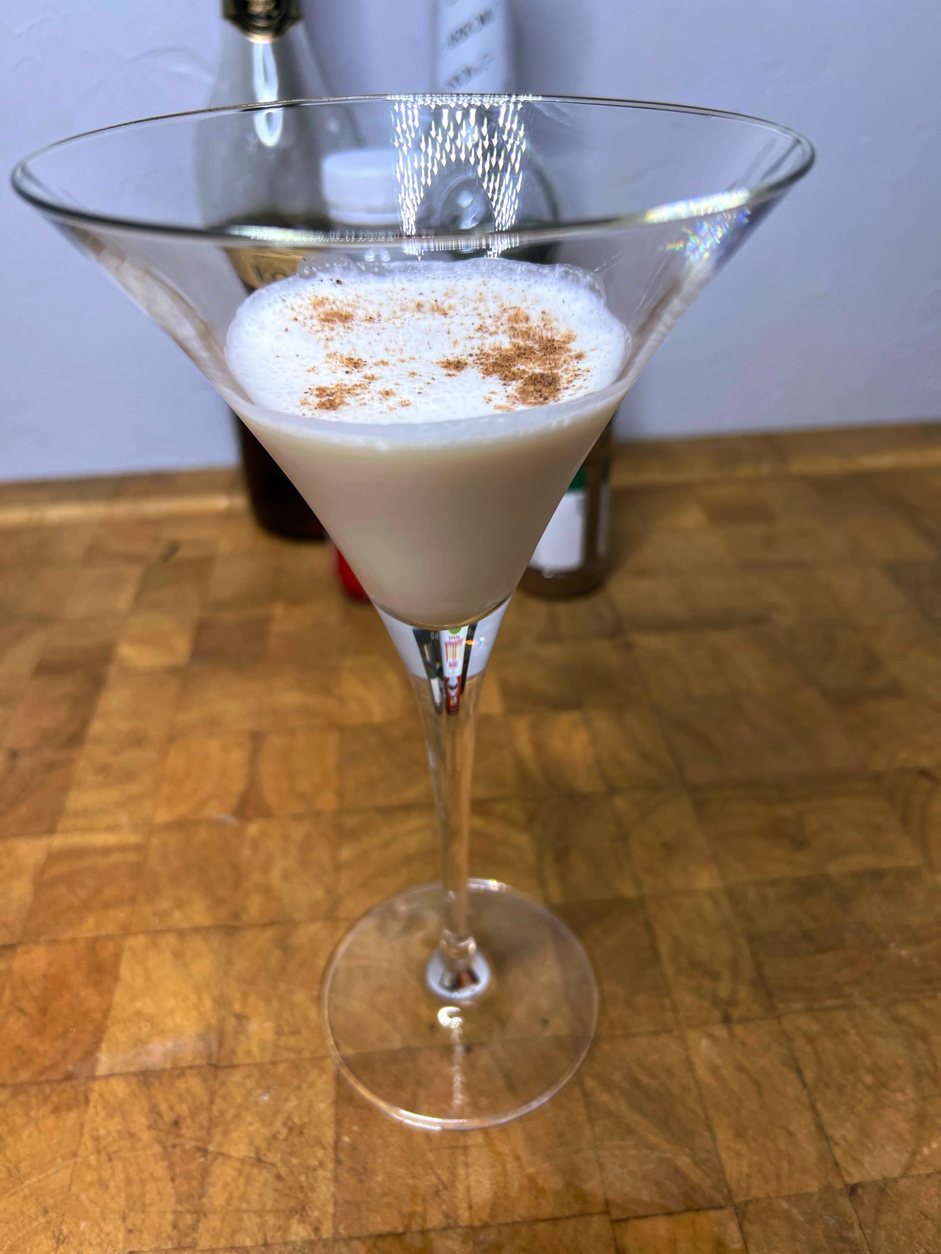 closeup of a brandy alexander drink in a martini glass with nutmeg on top.