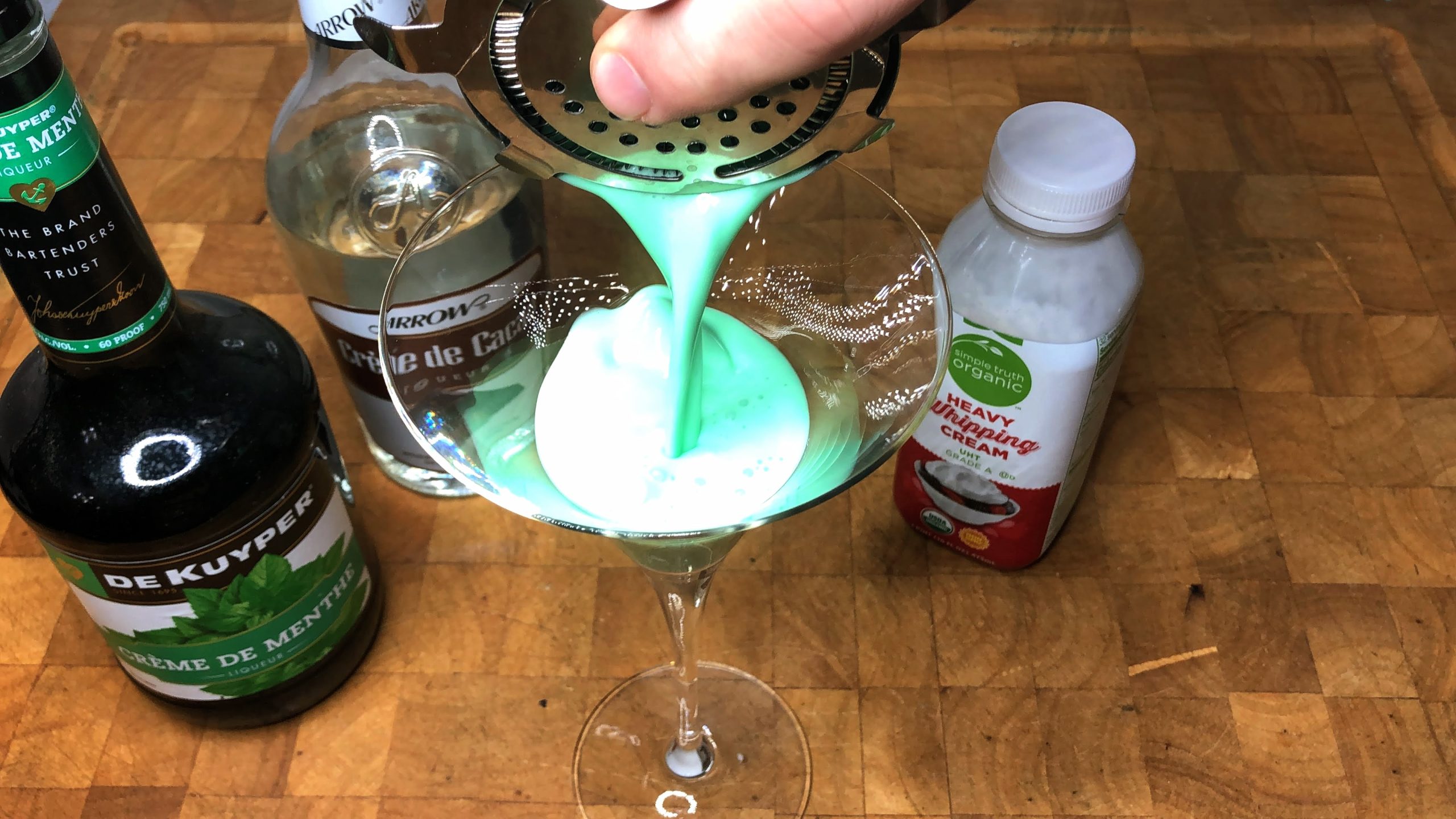 pouring grasshopper drink from shaker into a martini glass