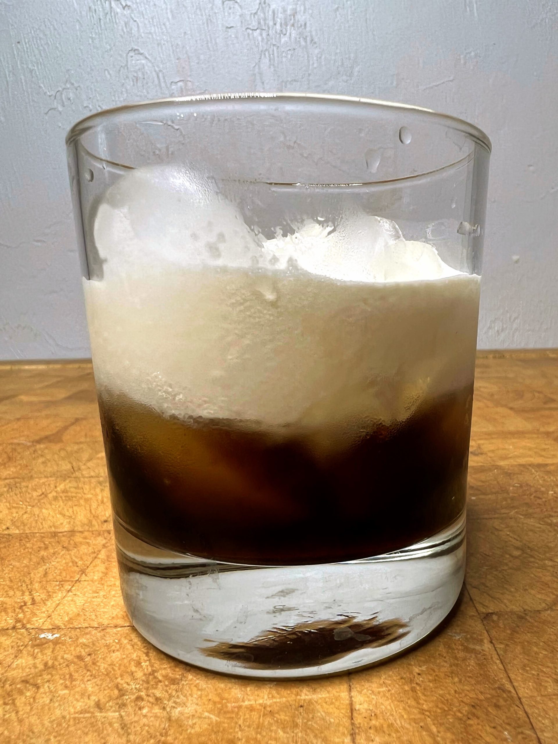 closeup of a kahlua and cream in a rocks glass on a wooden table