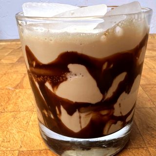 closeup of mudslide cocktail with chocolate syrup on a wooden table