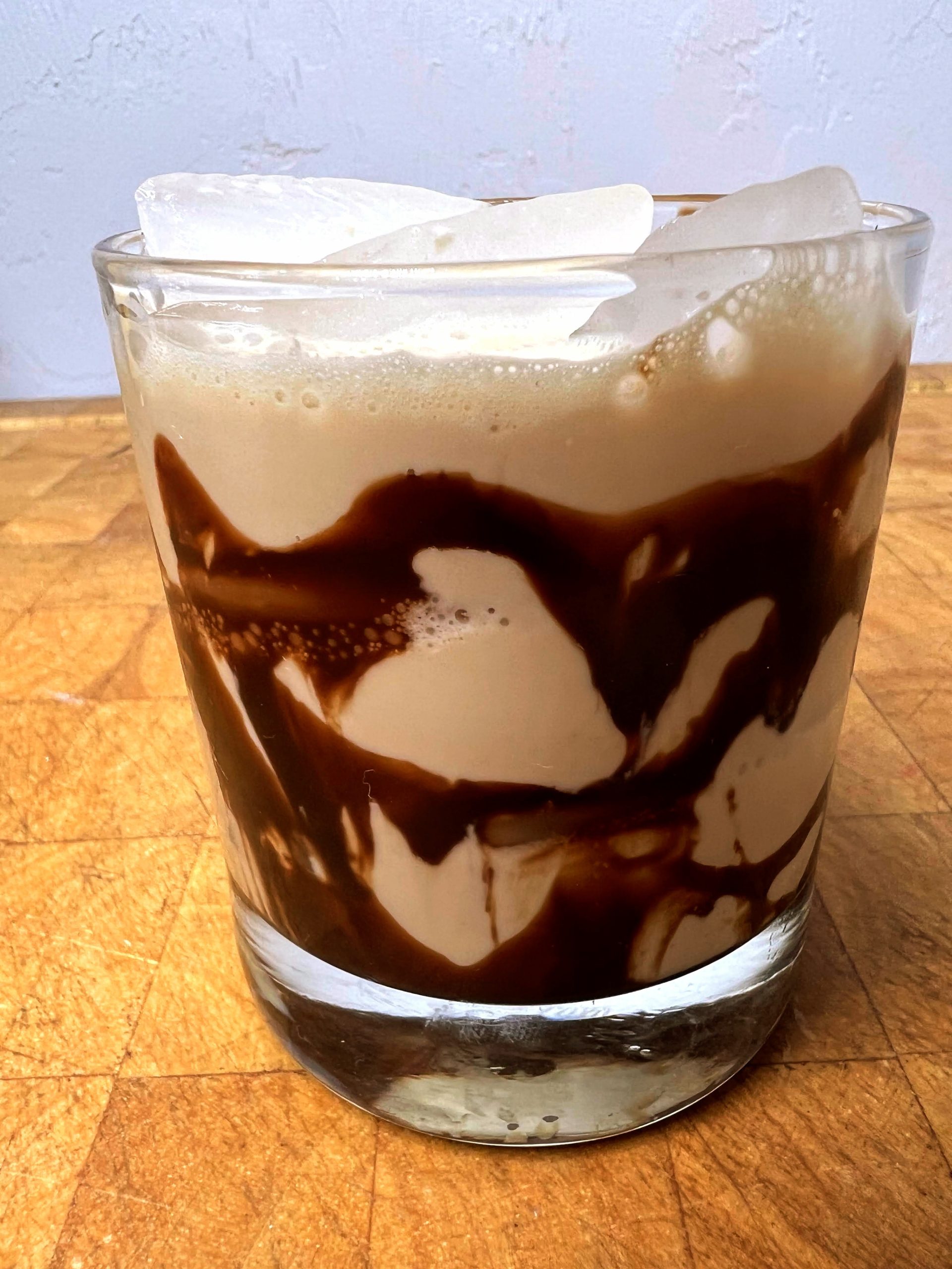 closeup of mudslide cocktail with chocolate syrup on a wooden table