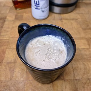amaretto coffee in a coffee mug on a wooden table with ingredients in the background
