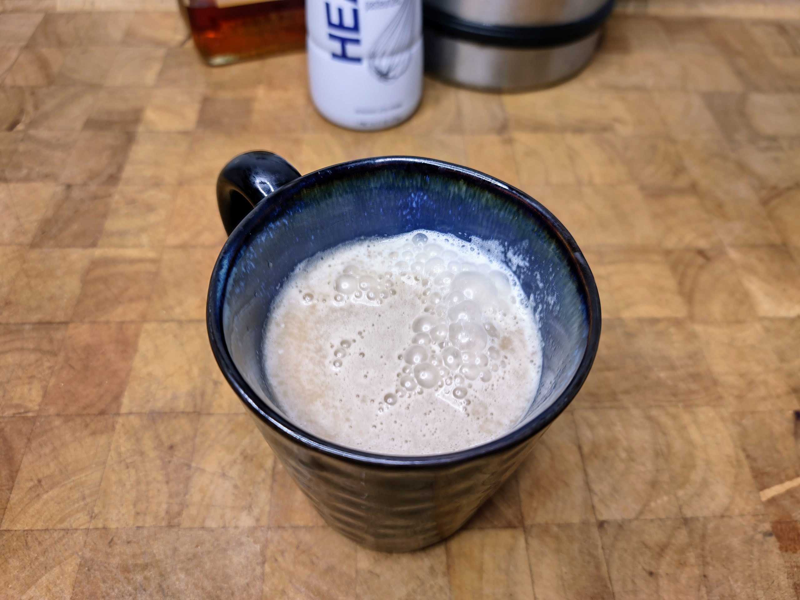amaretto coffee in a coffee mug on a wooden table with ingredients in the background