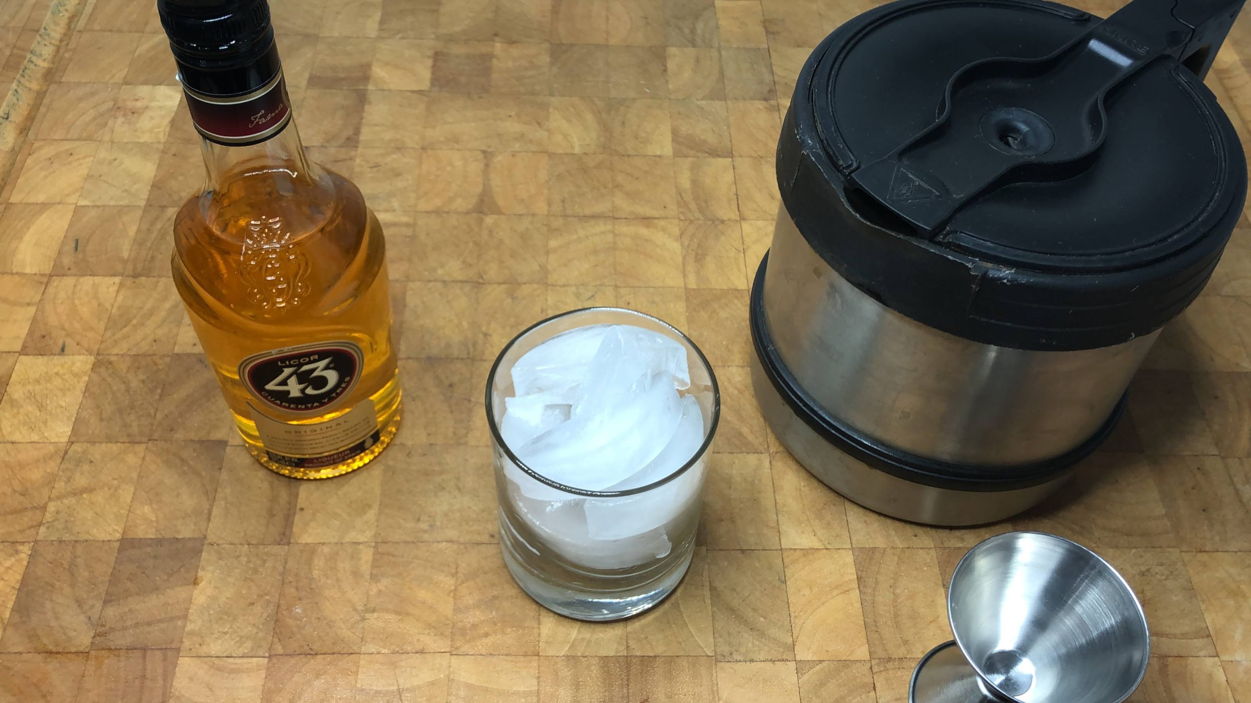 pot of espresso next to rocks glass with ice, jigger and licor 43