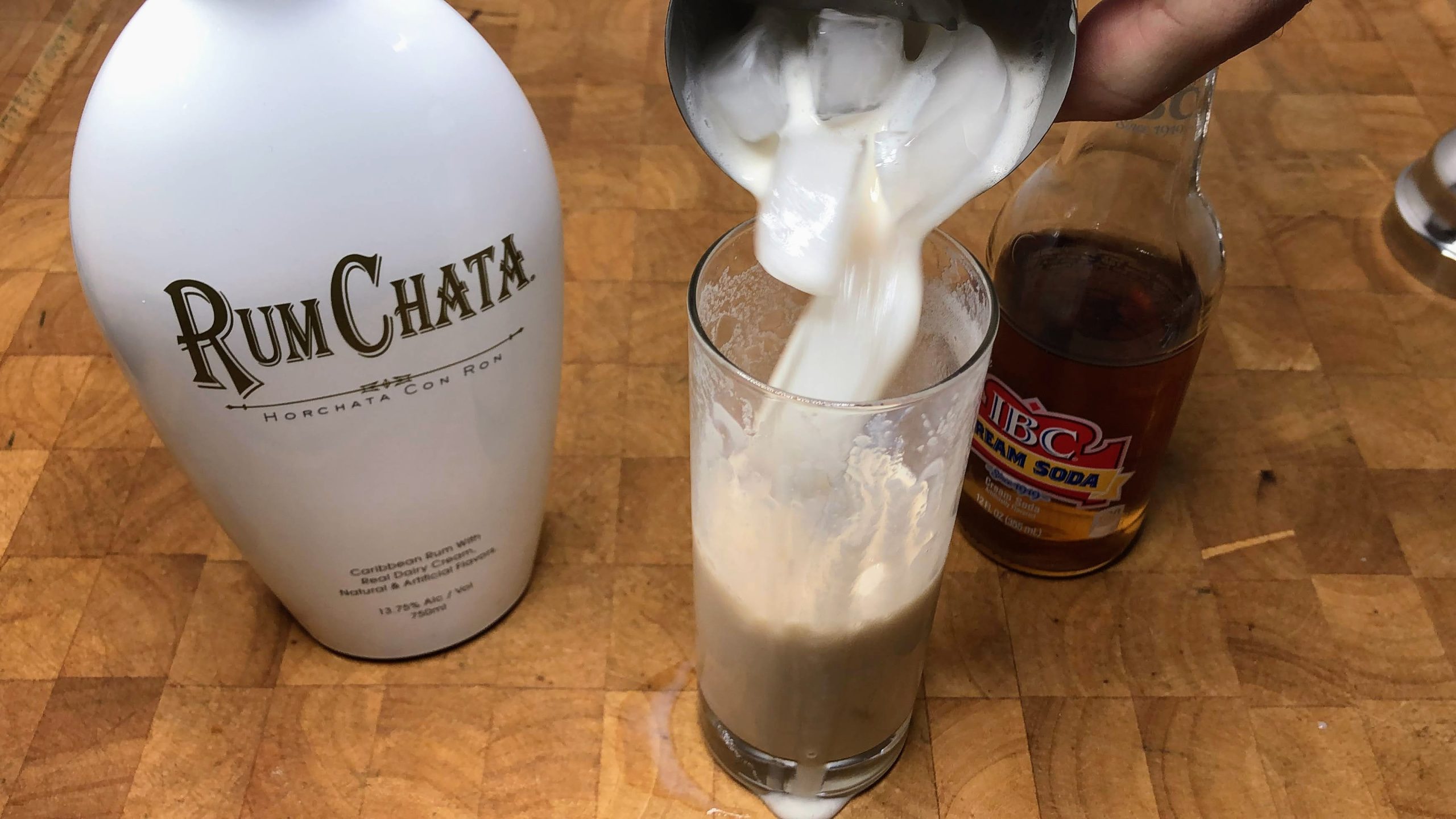 pouring rumchata and cream soda from shaker into glass