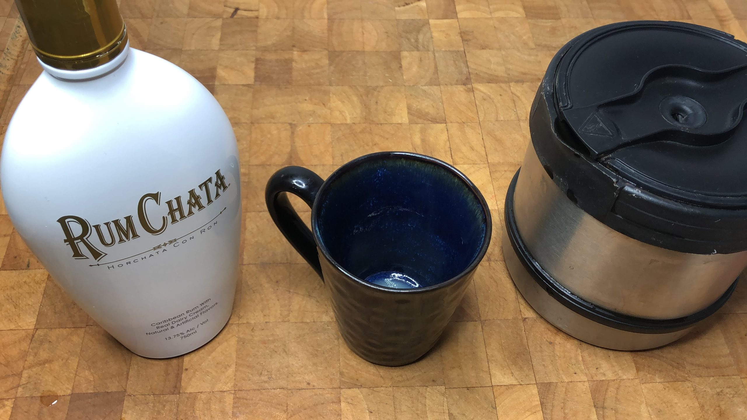 coffee mug, coffee pot and bottle of rumchata on a wooden table