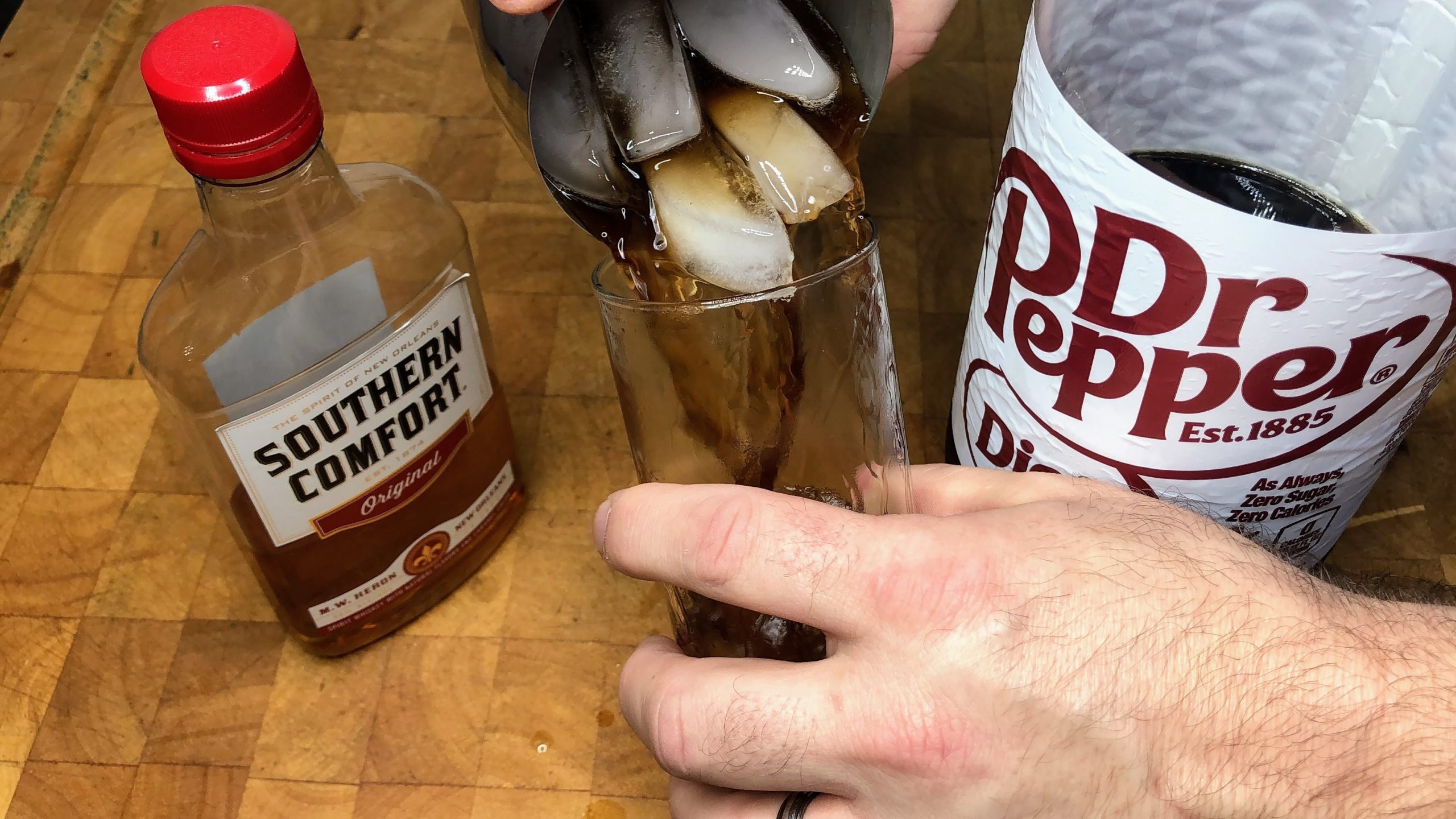 pouring southern comfort and dr. pepper from shaker into a glass