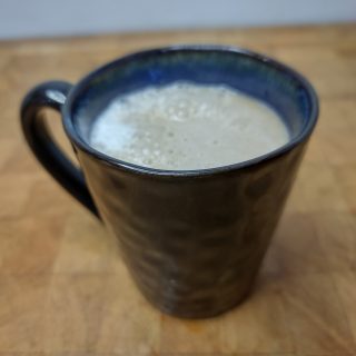 closeup of spiced rum coffee in a mug on a wooden table