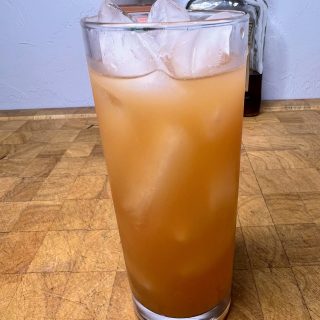 amaretto and grapefruit juice in a highball glass on a wooden table with ingredients in the background