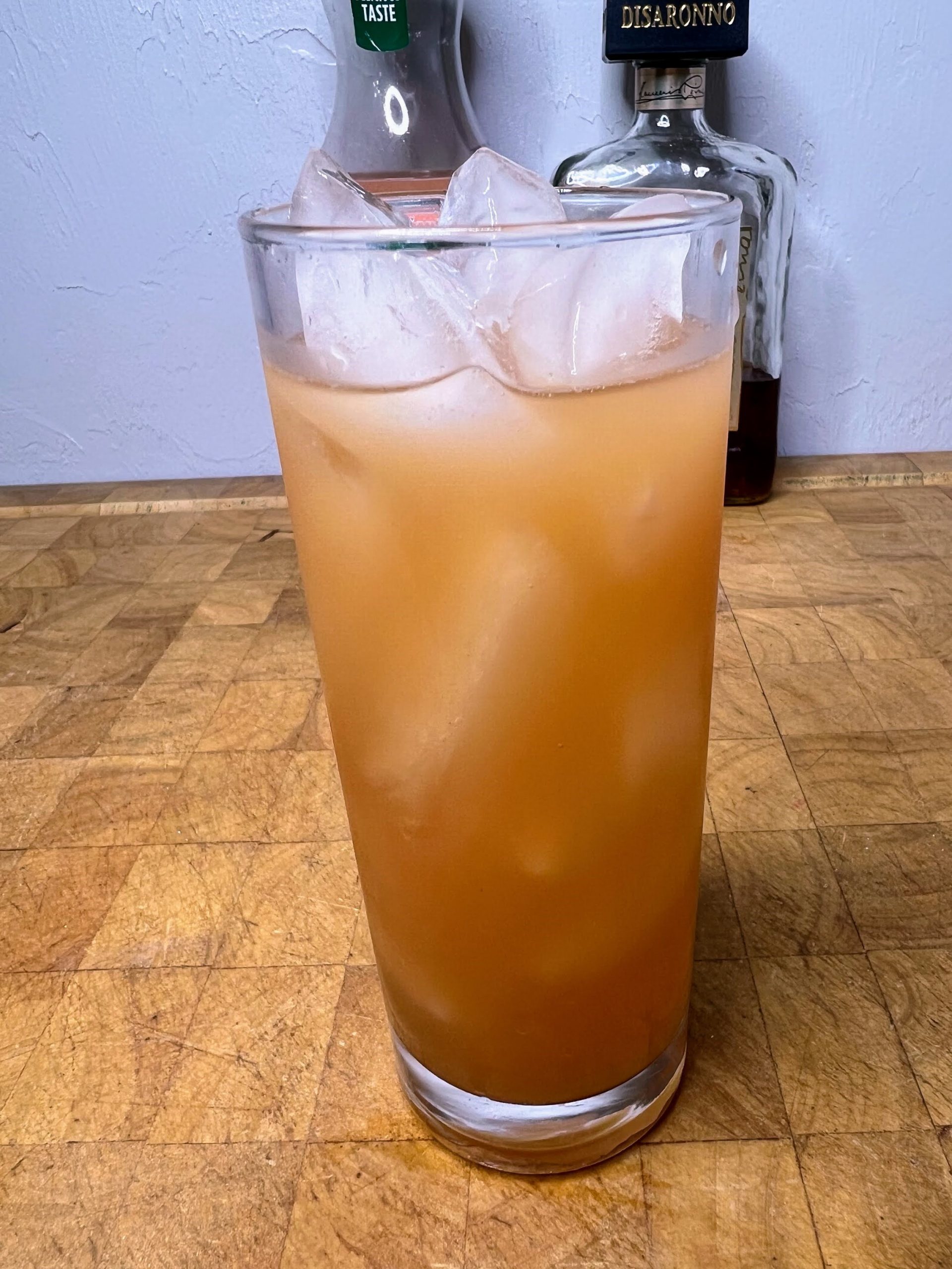 amaretto and grapefruit juice in a highball glass on a wooden table with ingredients in the background