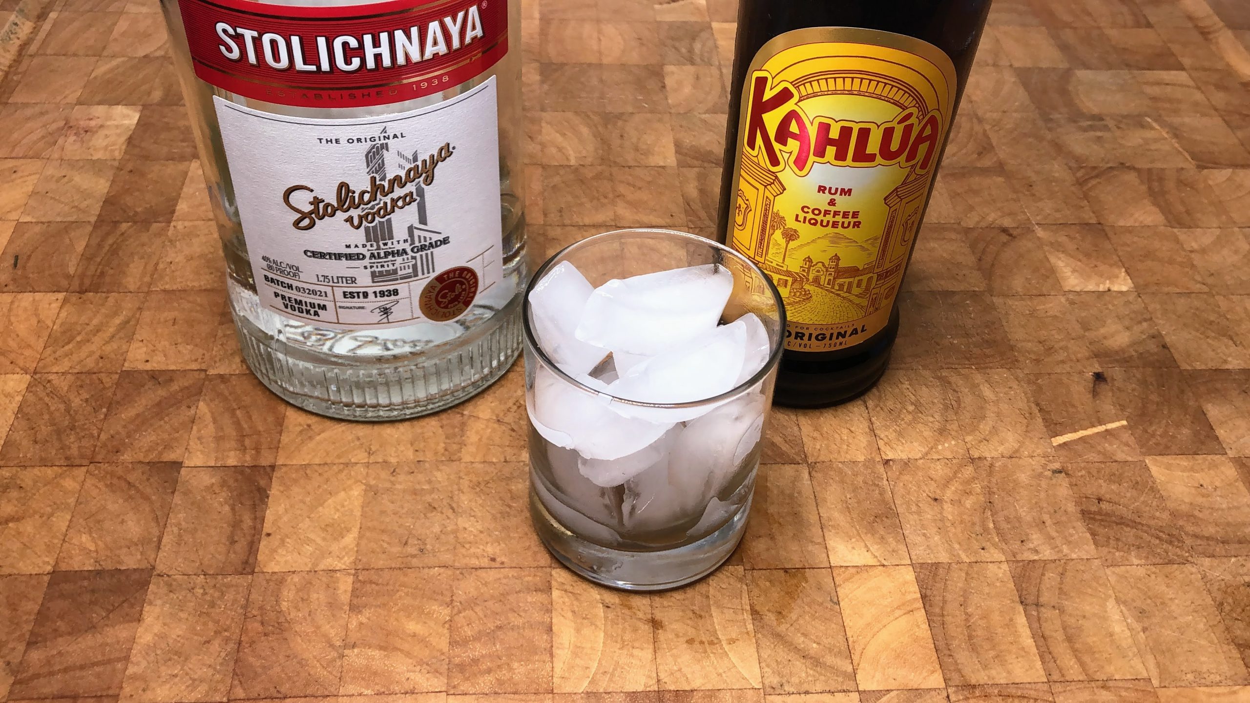 rocks glass with ice next to bottles of kahlua and vodka