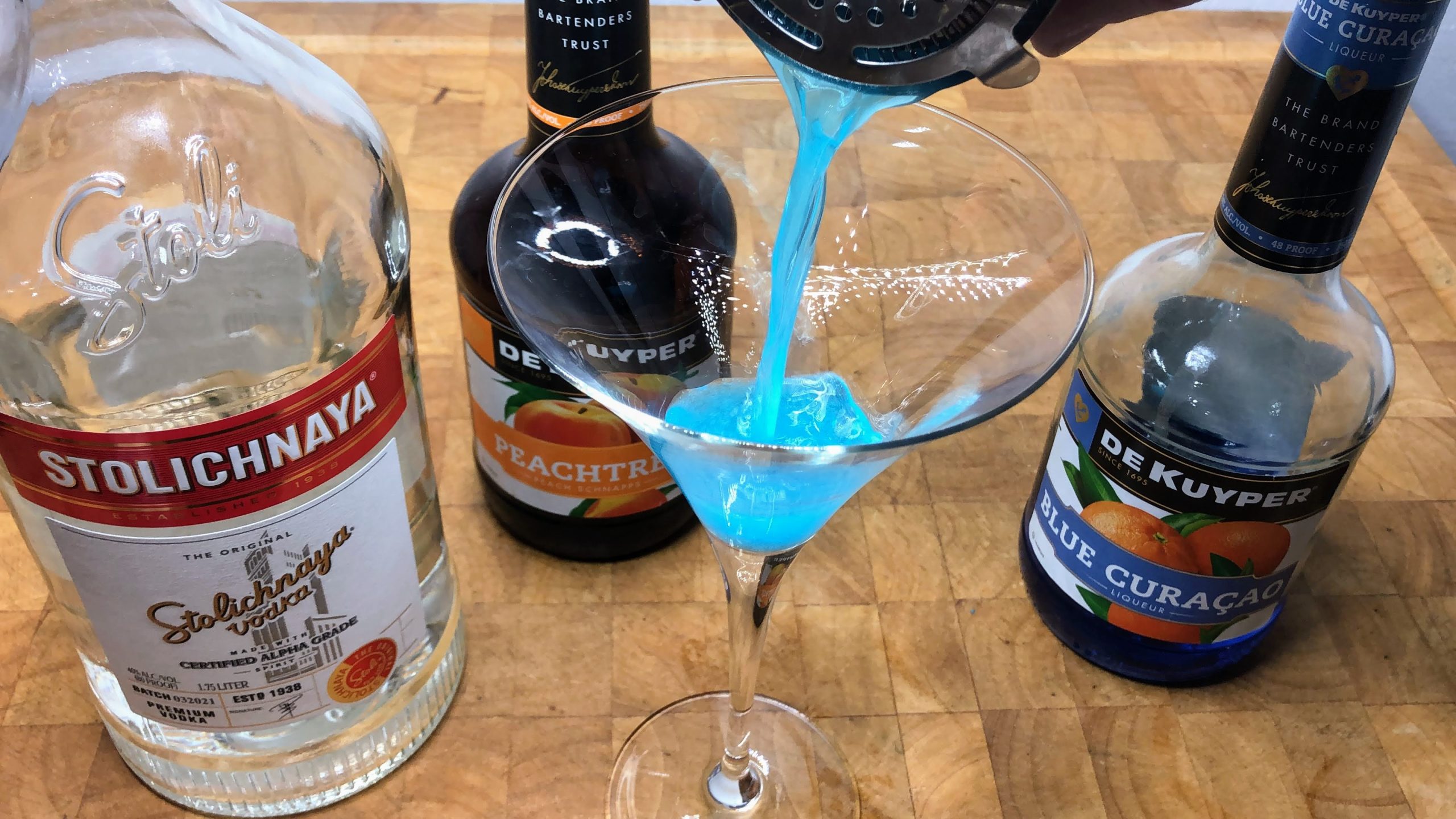 pouring blue dolphin drink into martini glass