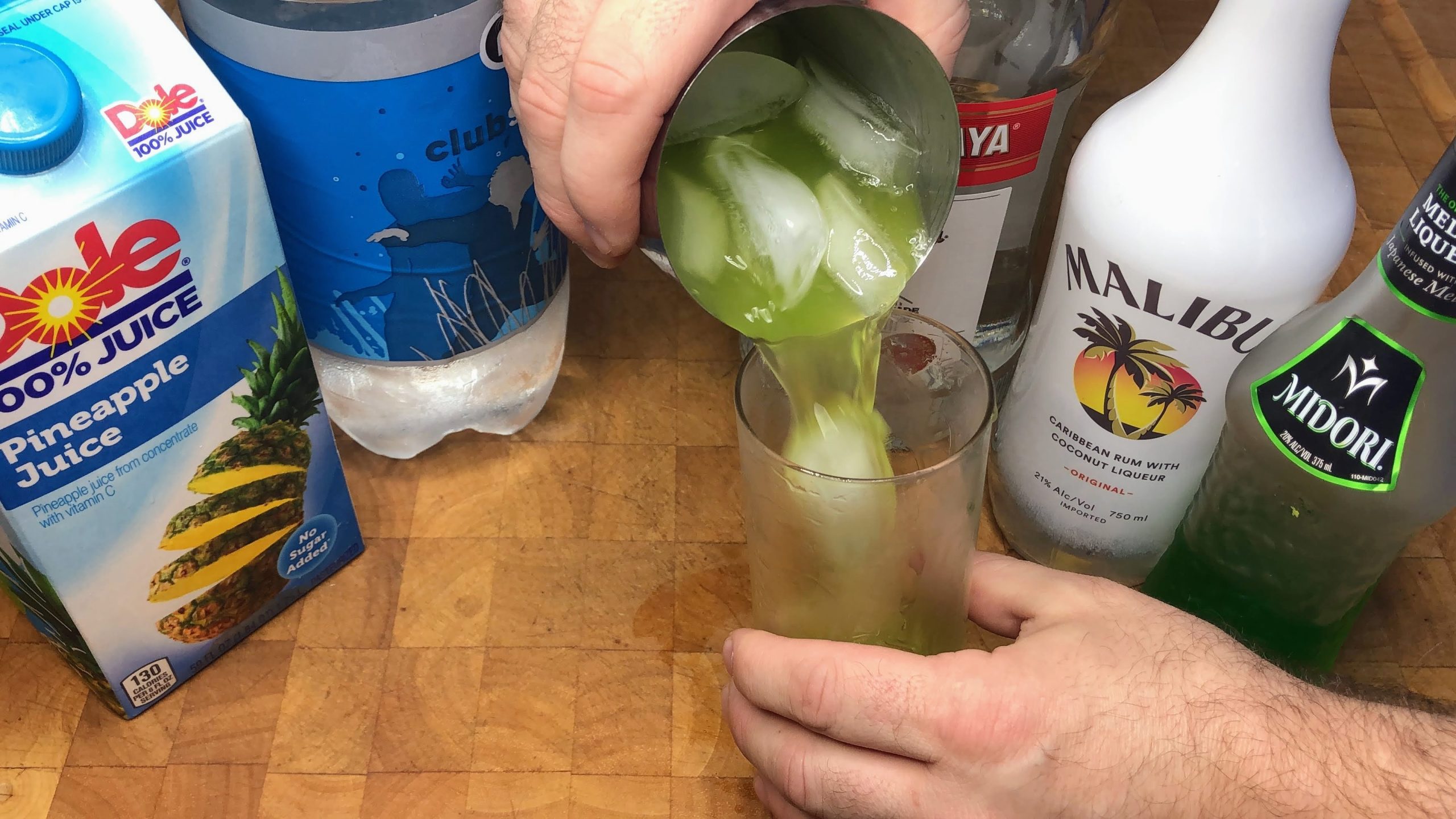 pouring cactus juice cocktail from shaker into glass