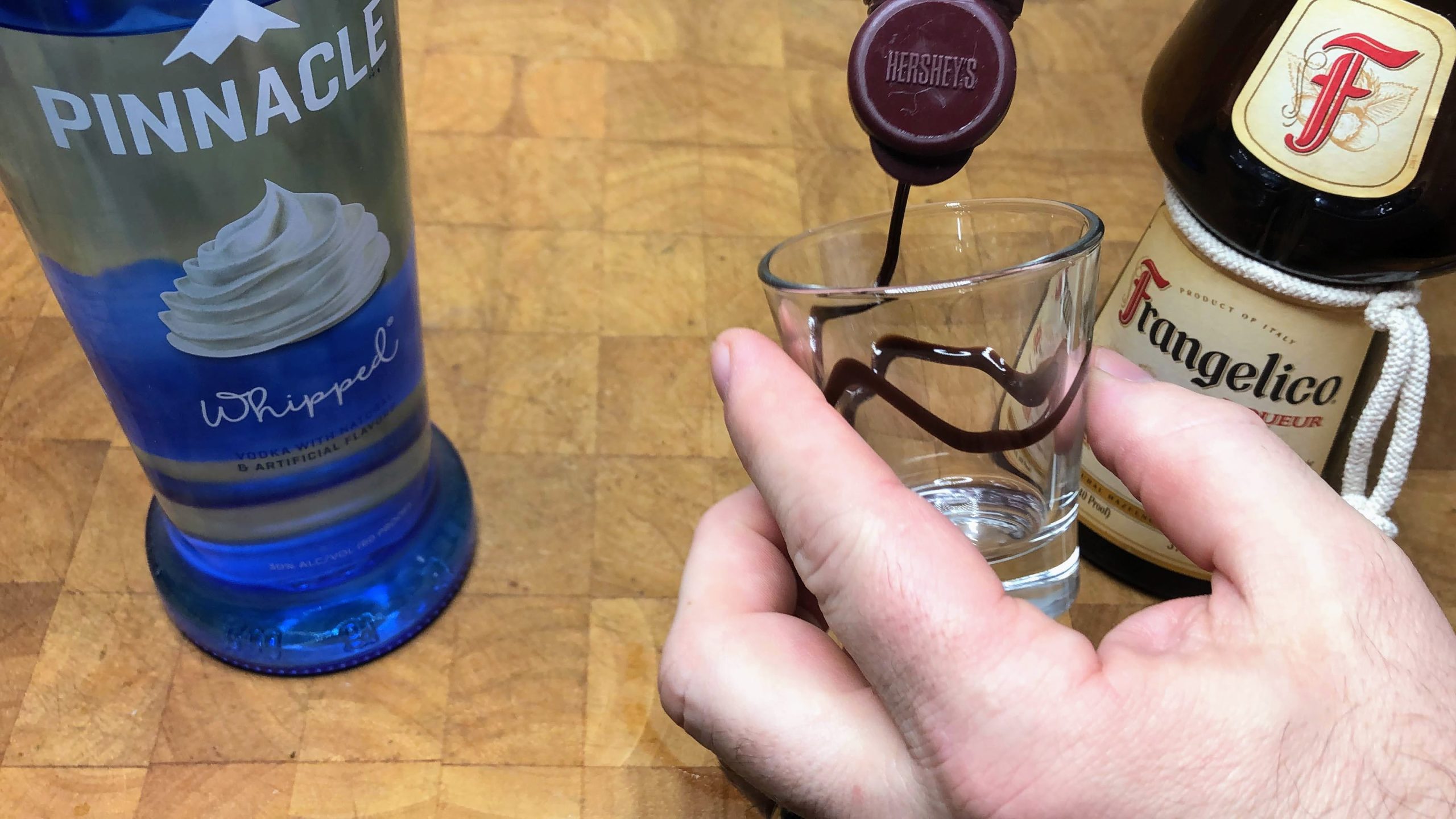 drizzling chocolate syrup inside a shot glass