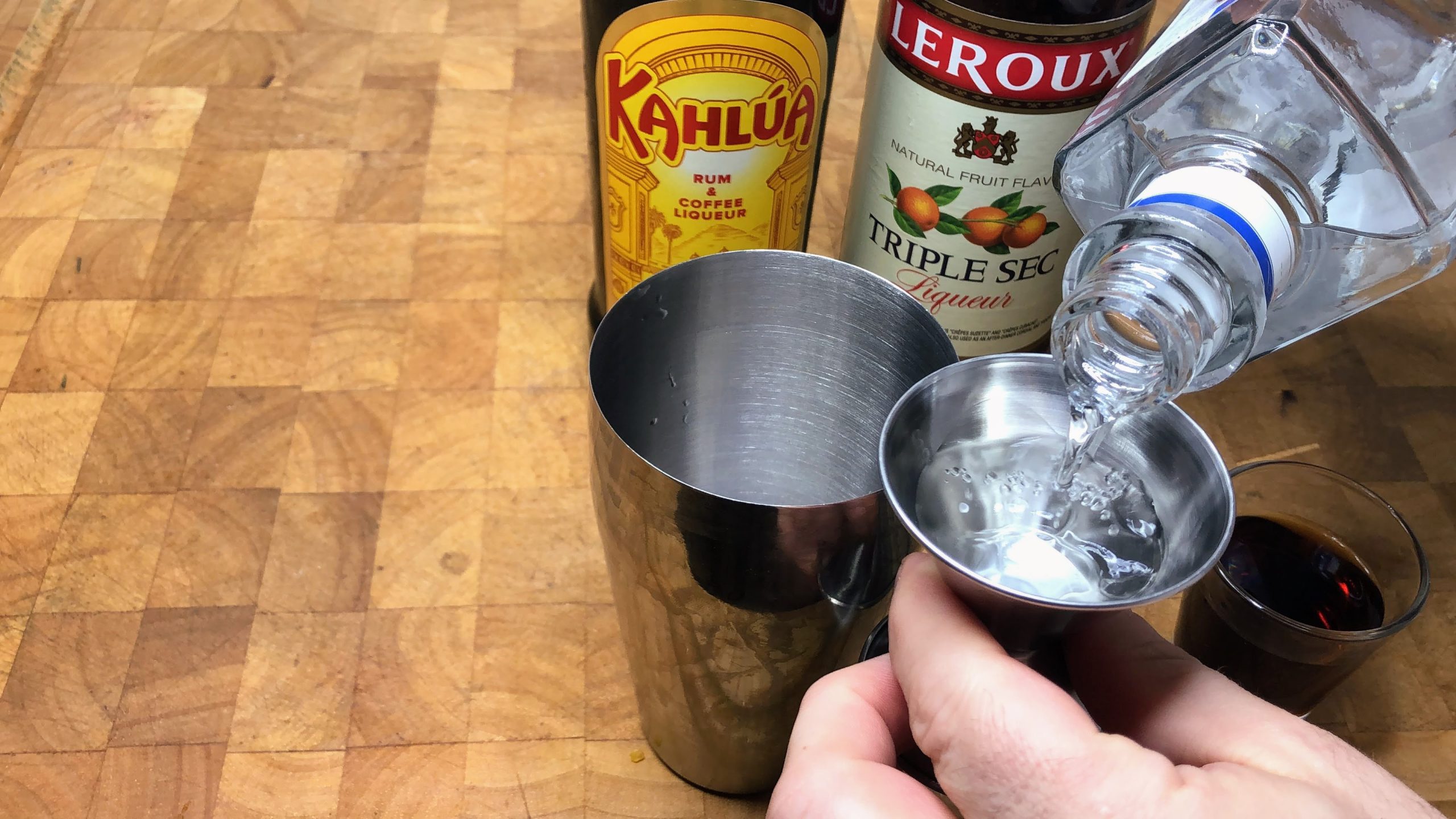 adding tequila to a jigger