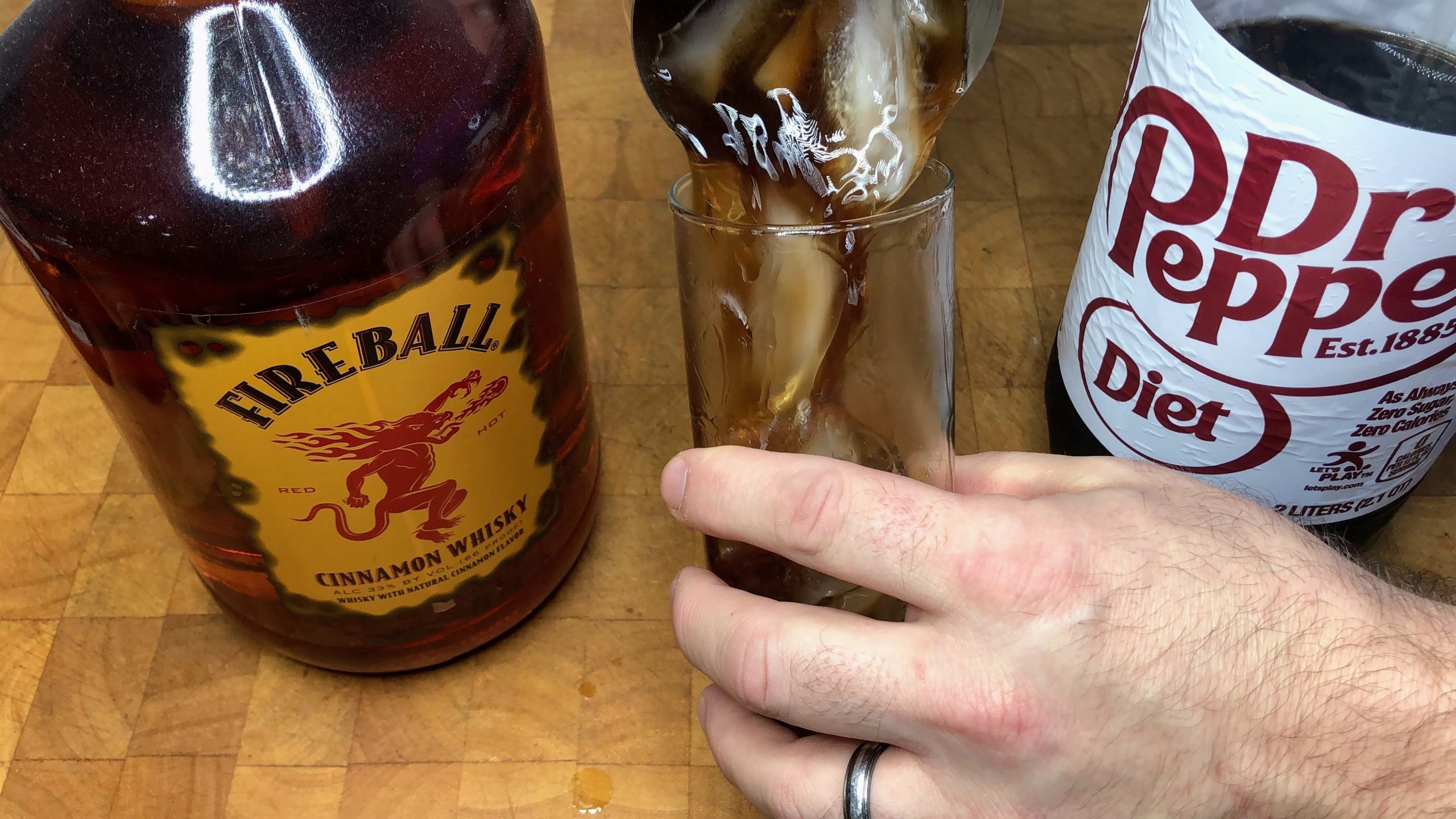 poiuring fireball and dr pepper from shaker into glass
