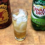 fireball and ginger ale in a glass with ingredient bottles next to the glass