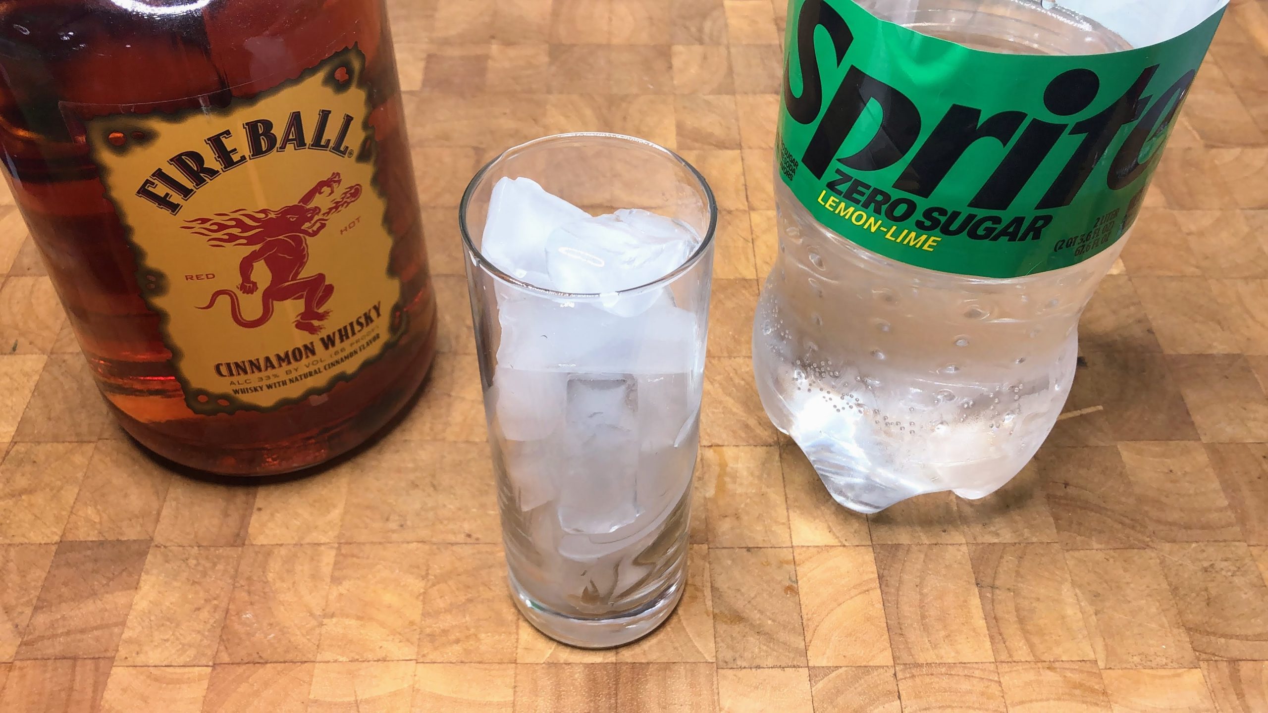 highball glass with ice next to bottles of sprite and fireball