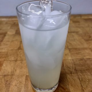 closeup of gin limeade in a highball glass on wooden table