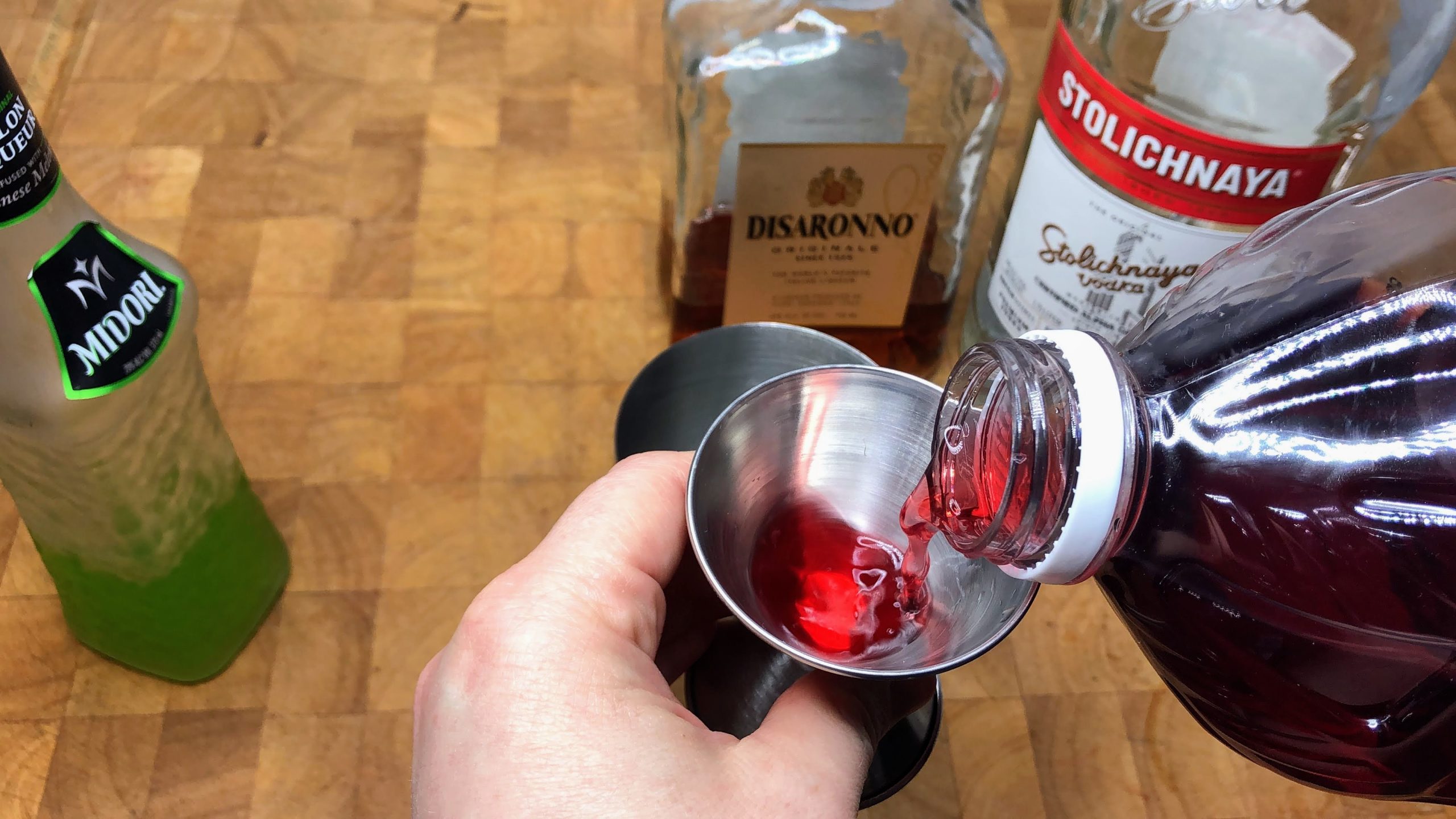measuring cranberry juice with a jigger