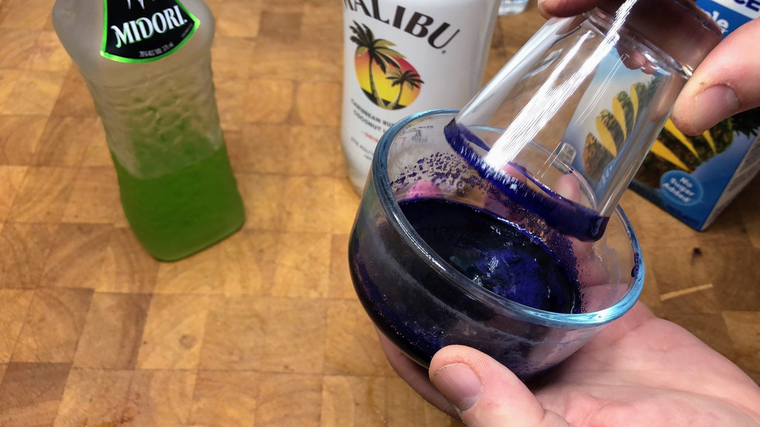 dipping shot glass in purple sugar on the rim