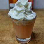 closeup of orange creamsicle shot topped with whipped cream