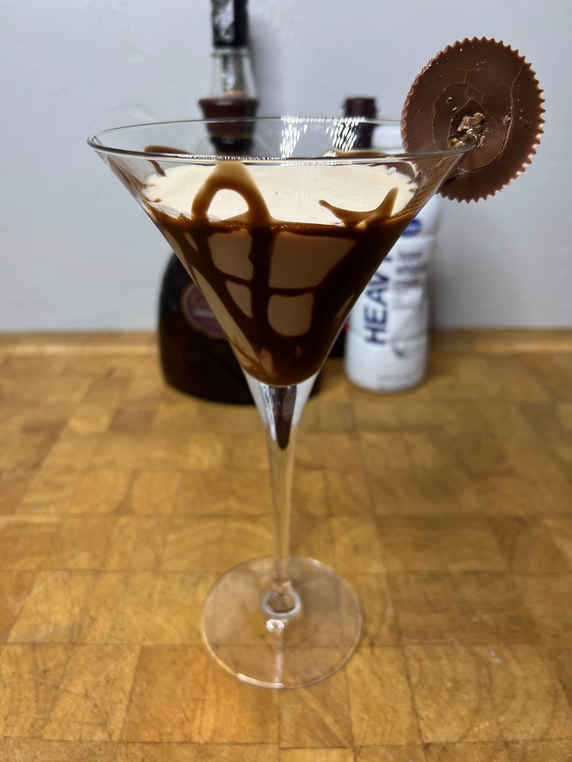 peanut butter cup martini on a wooden table with ingredient bottles in the background