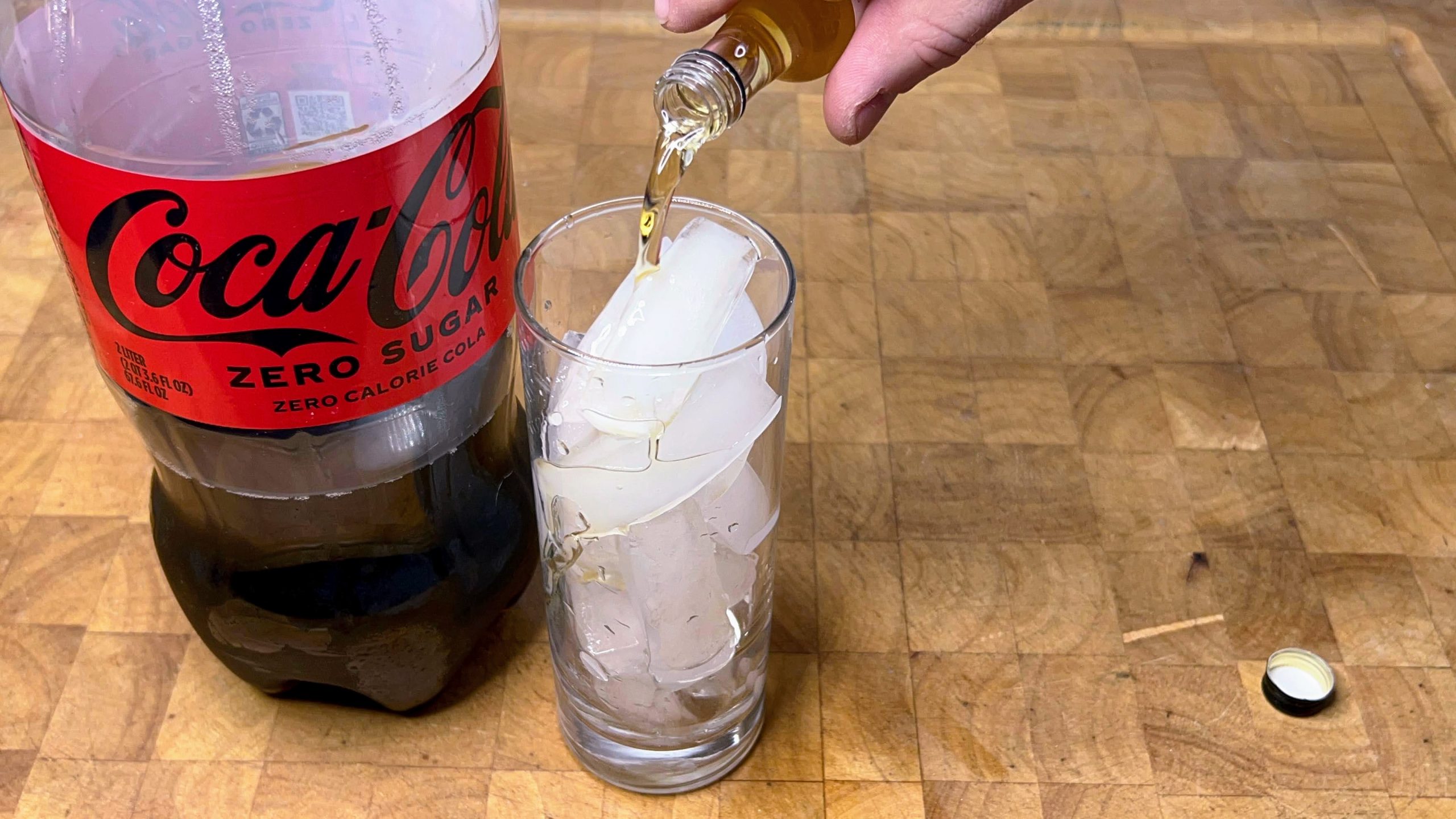pouring peanut butter whiskey into a highball glass