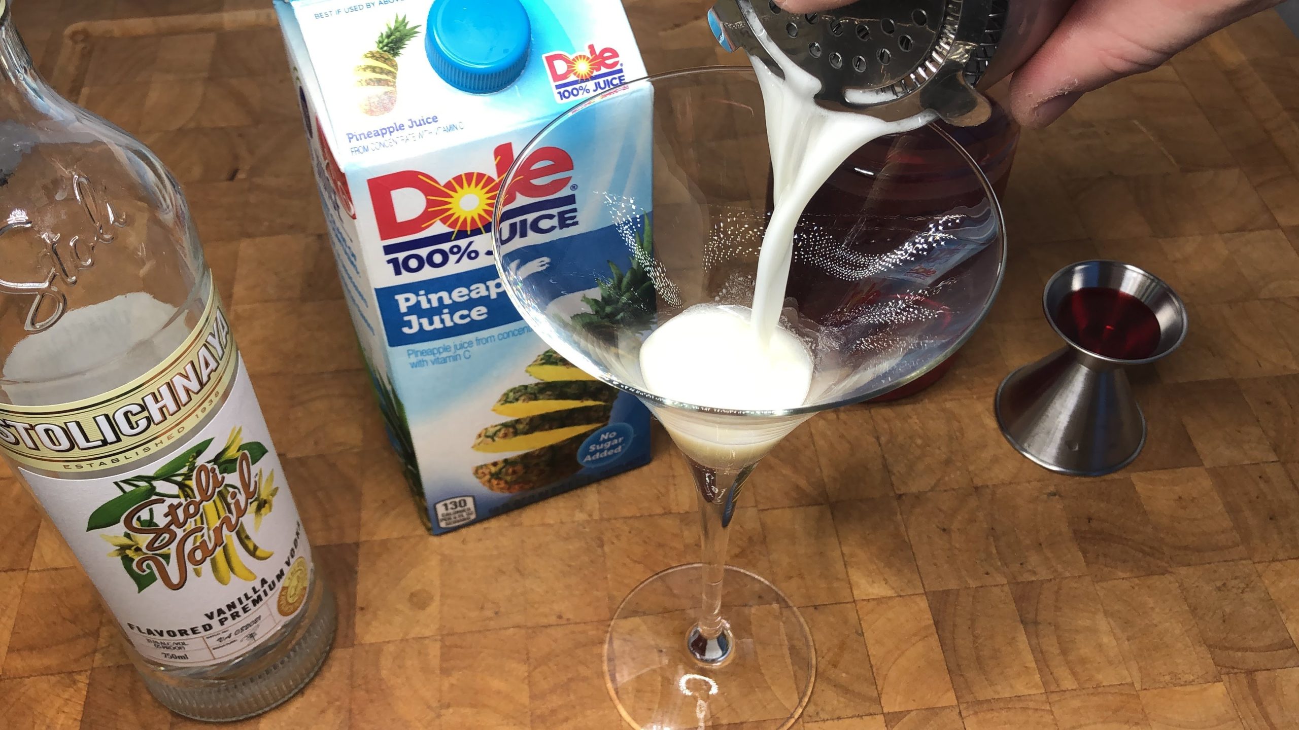 pouring pineapple upside down cake martini into glass