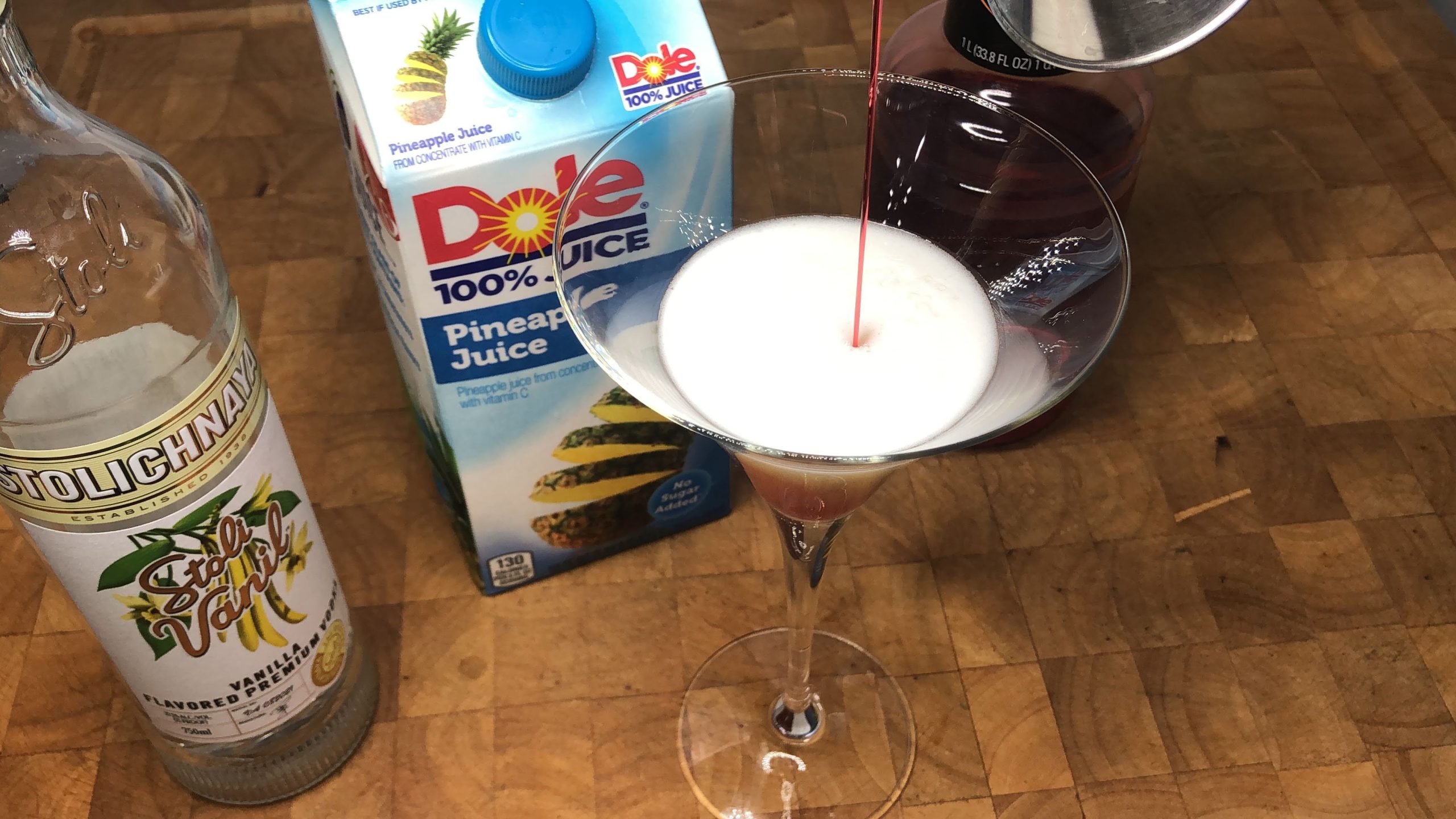 pouring grenadine into martini glass.