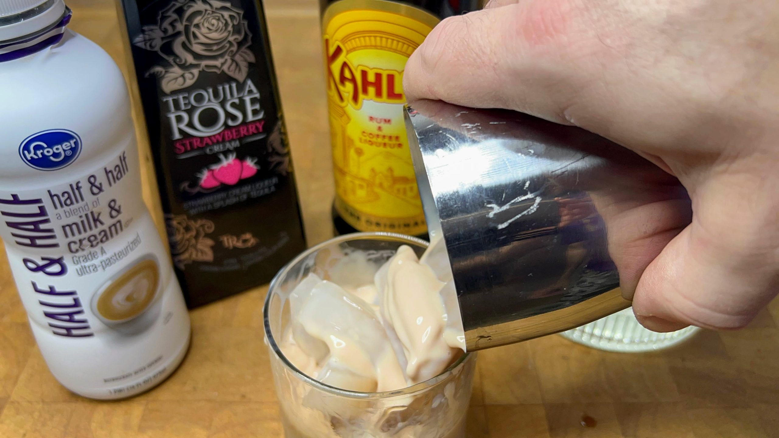 pouring pink russian cocktail from shaker into rocks glass
