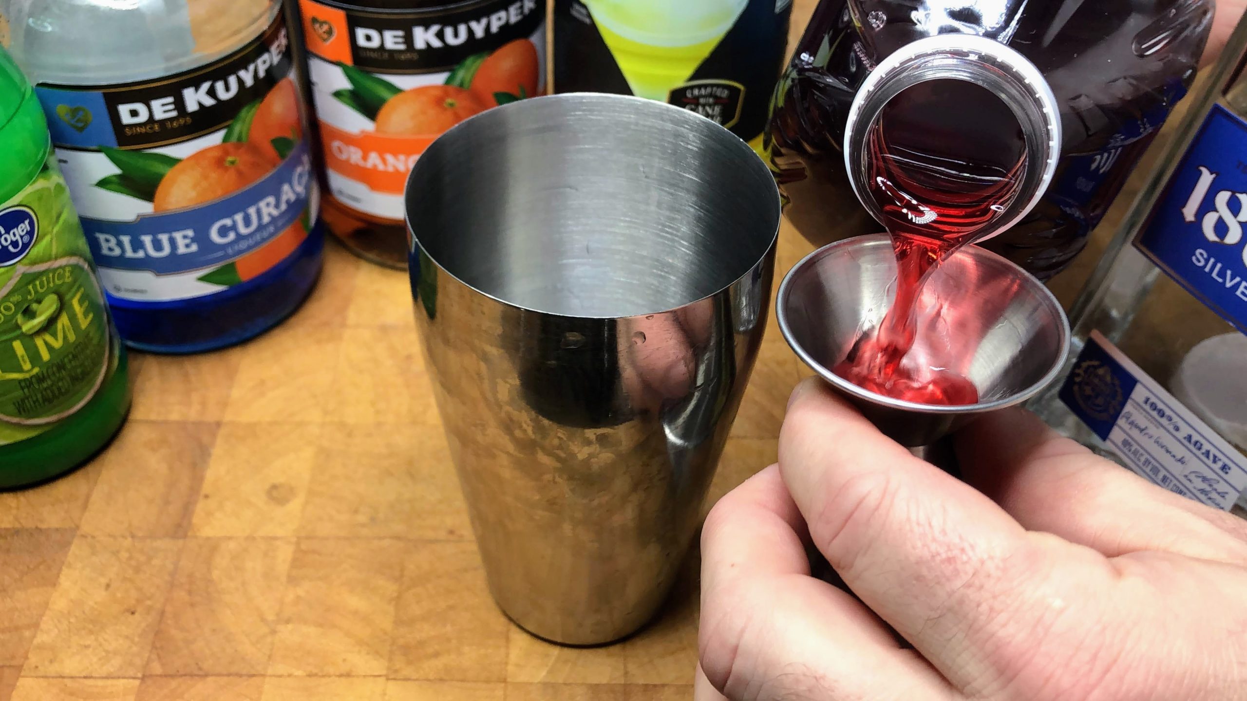 measuring cranberry juice with a jigger
