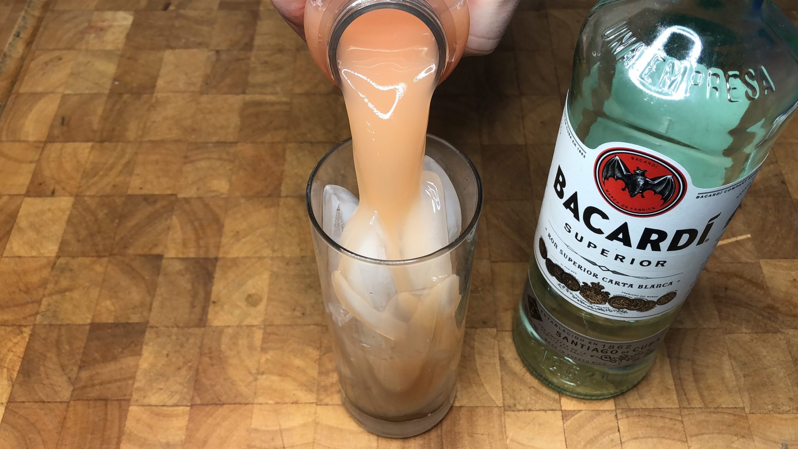 pouring grapefruit juice into a highball glass