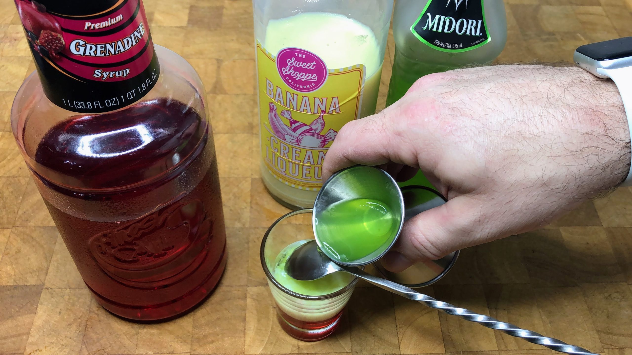 pouring midori over the back of a bar spoon