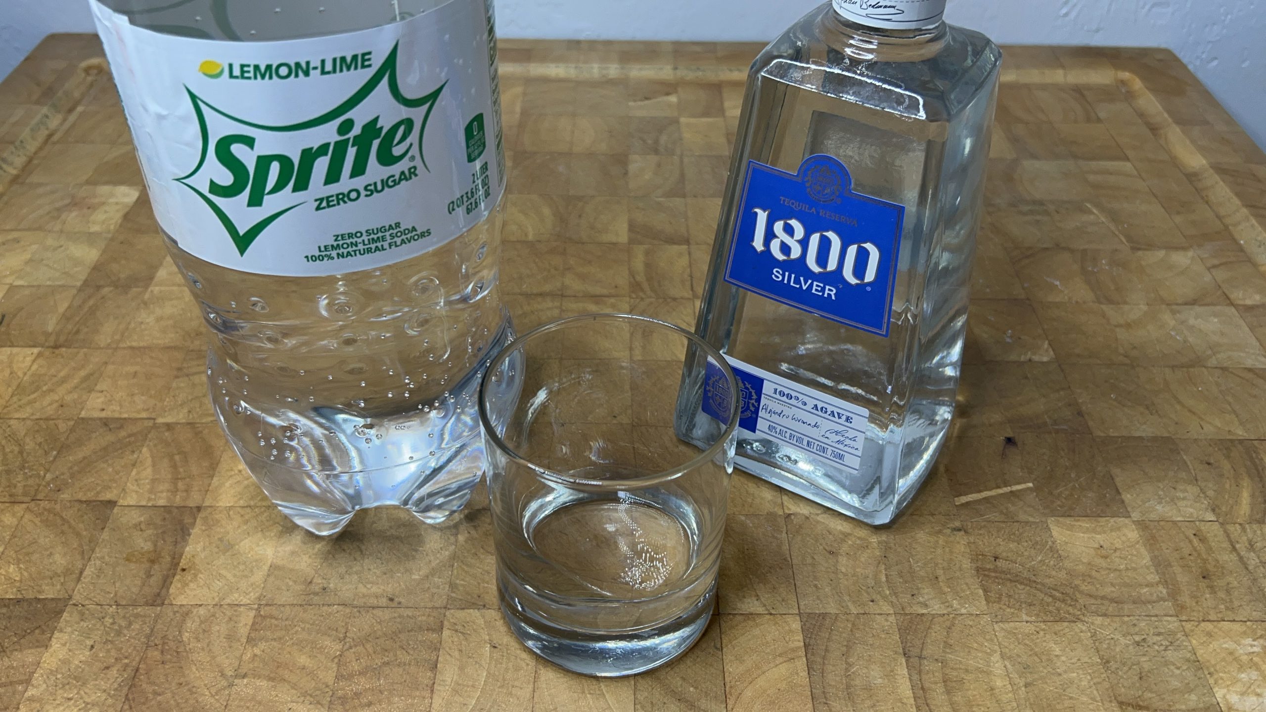 empty rocks glass next to sprite and tequila