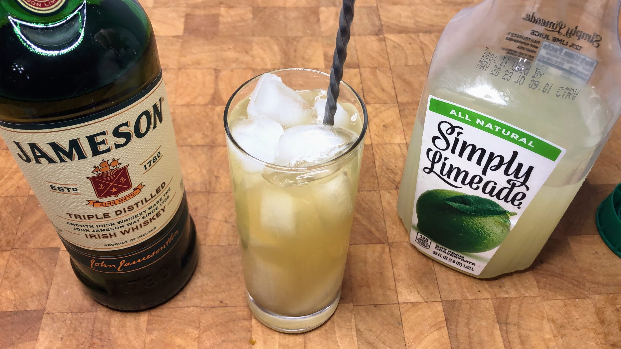stirring whiskey and limeade with a bar spoon