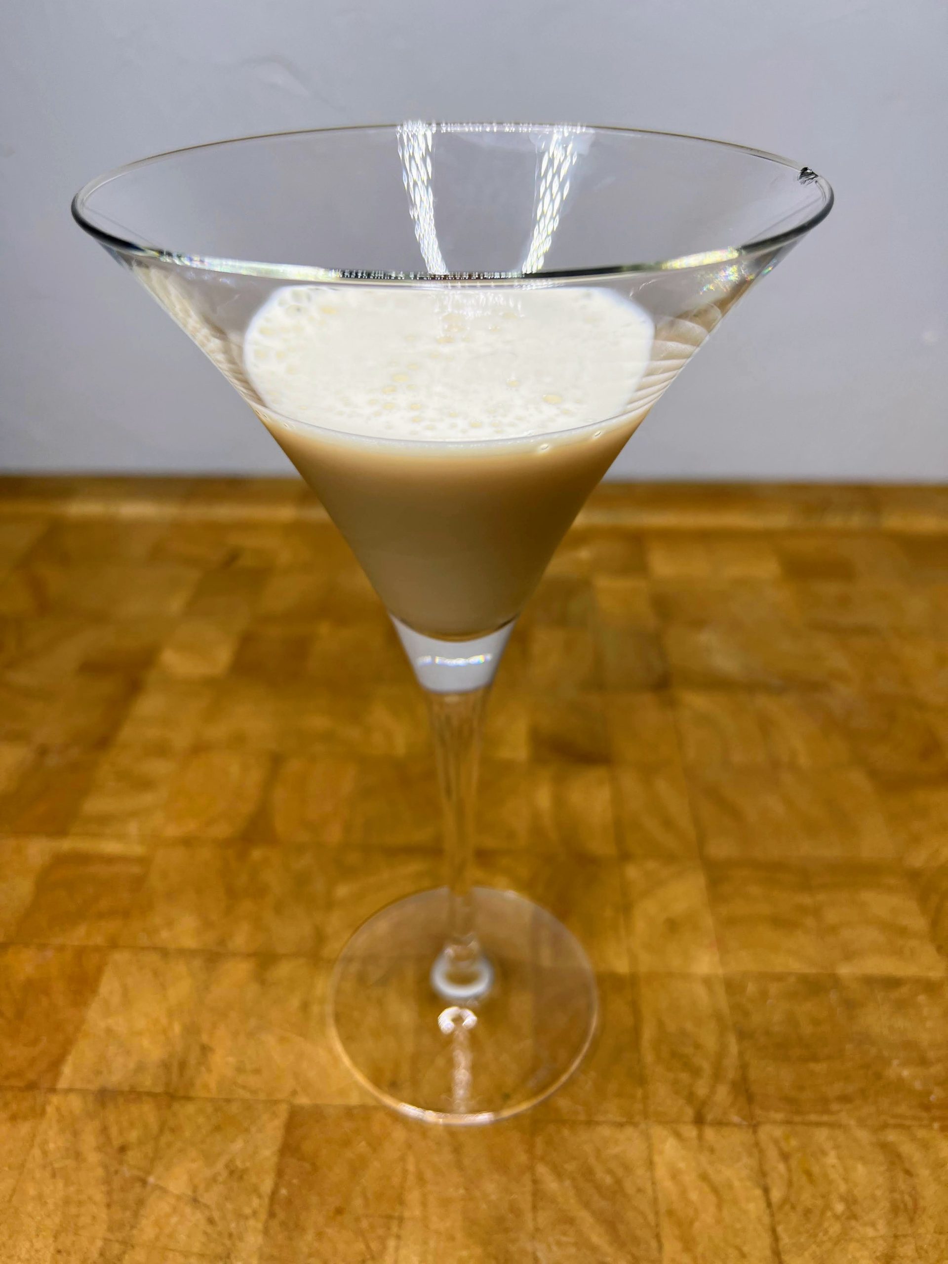 closeup of a banana cream martini in a martini glass on a wooden table