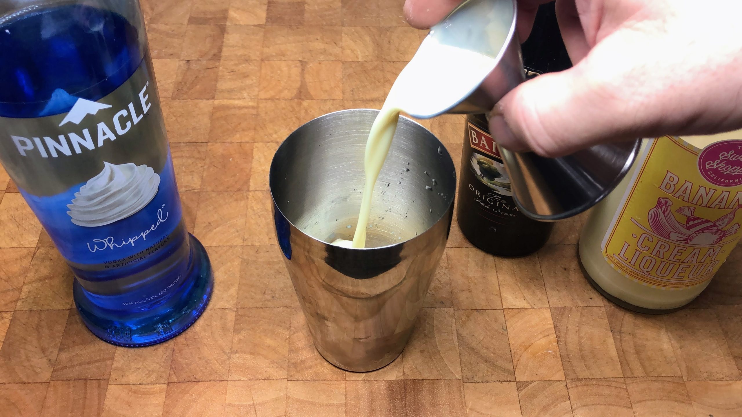 pouring banana liqueur into a shaker.