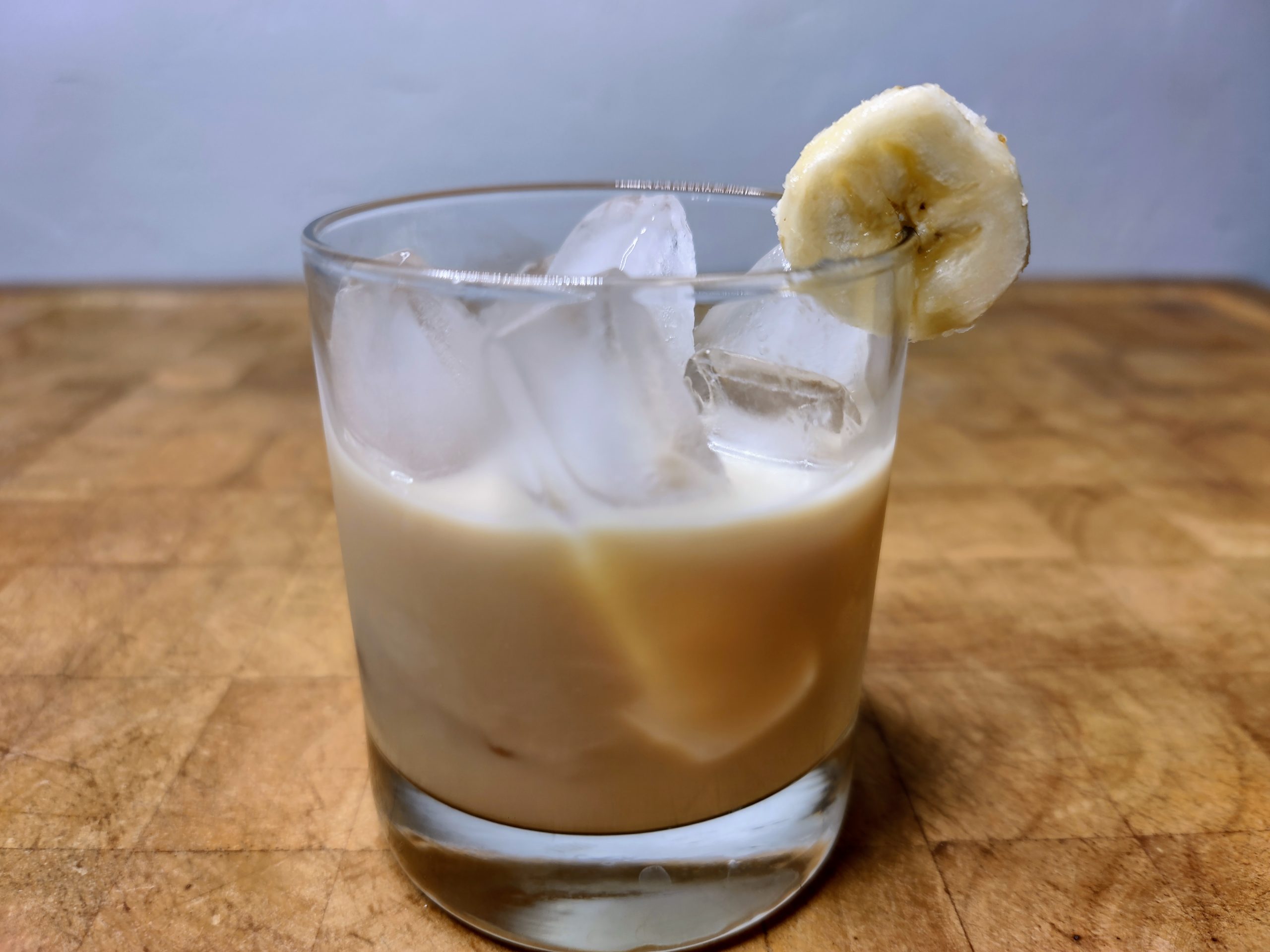 Banana foster cocktail in a rocks glass with a banana slice on the rim.