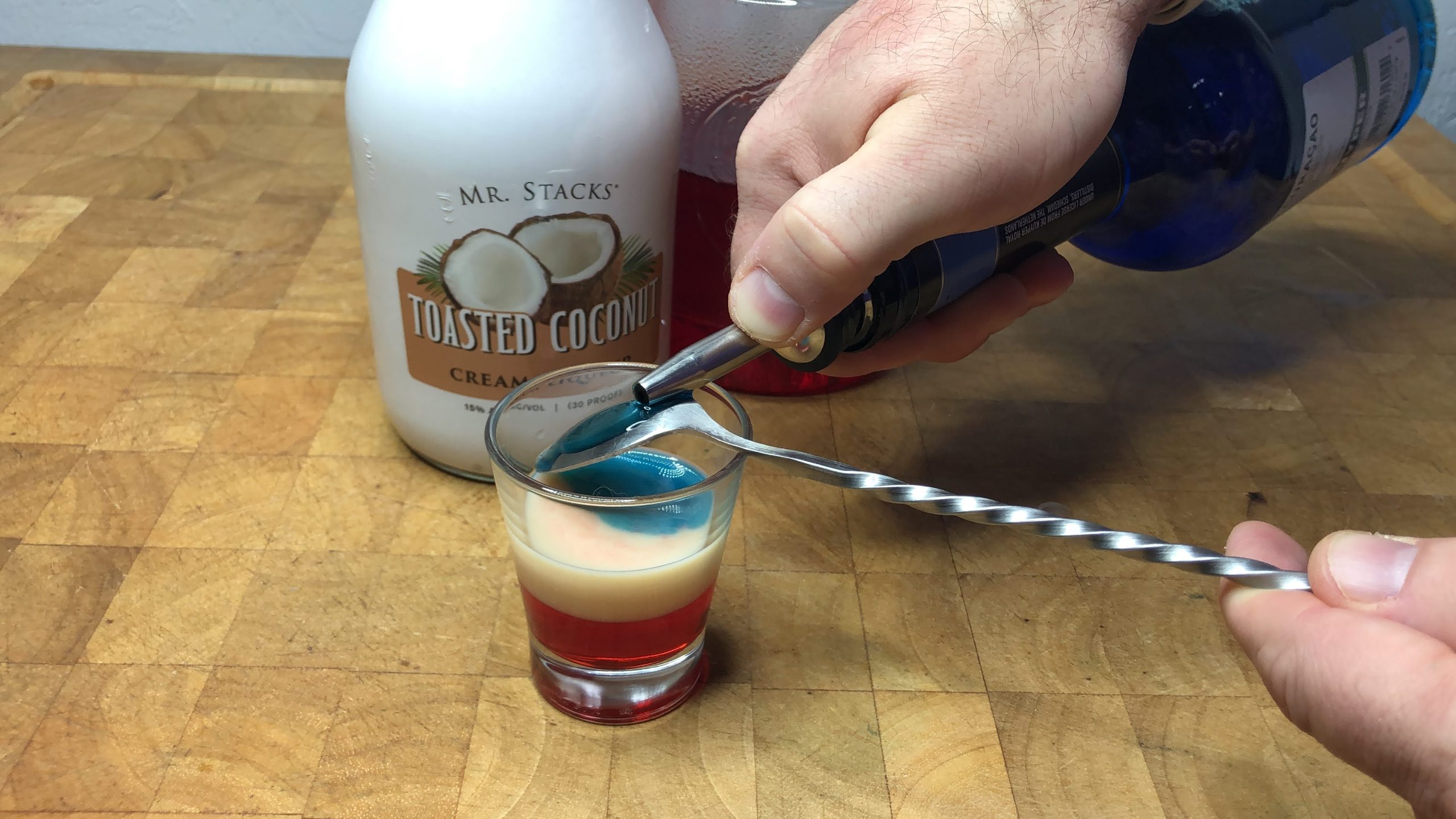 Layering blue curacao over the back of a bar spoon.