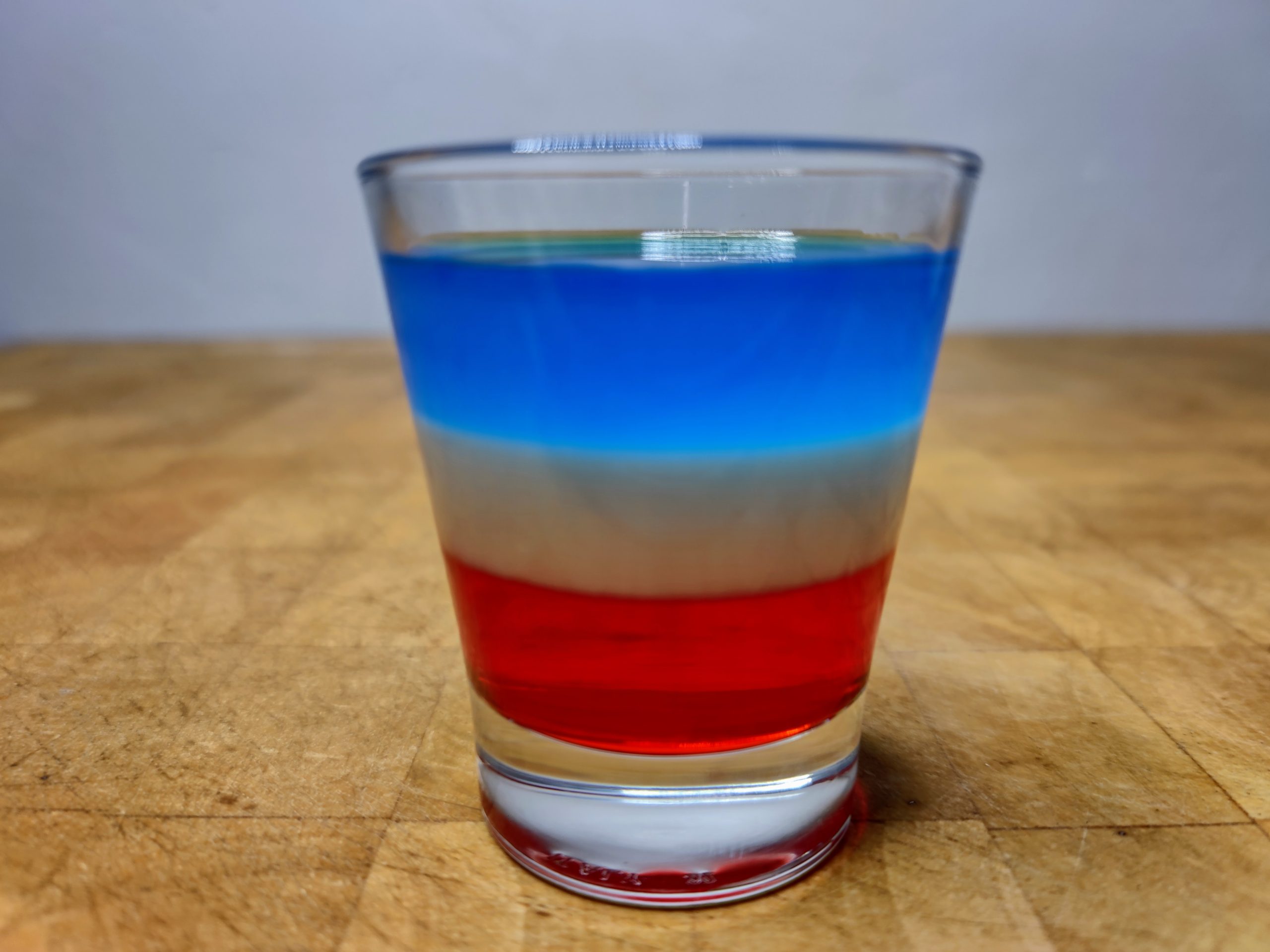 Bomb pop shot in a shot glass on a wooden table.