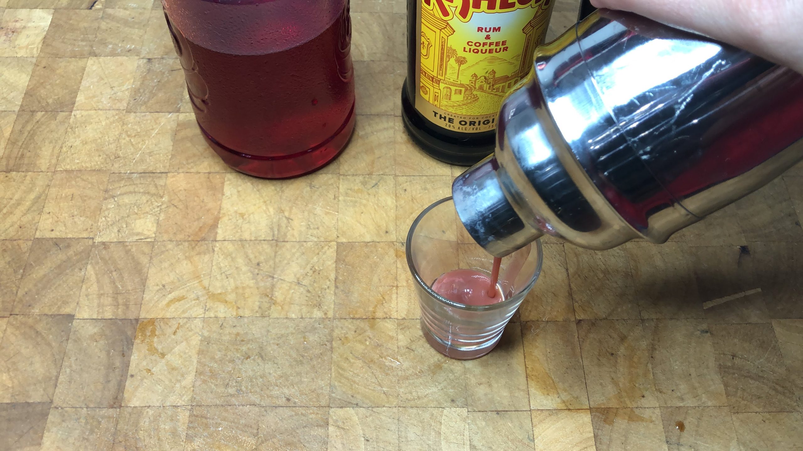 Pouring chocolate covered cherry shot from shaker into a shot glass.