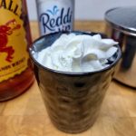 Fireball hot chocolate in a mug with whipped cream and ingredients next to the mug.