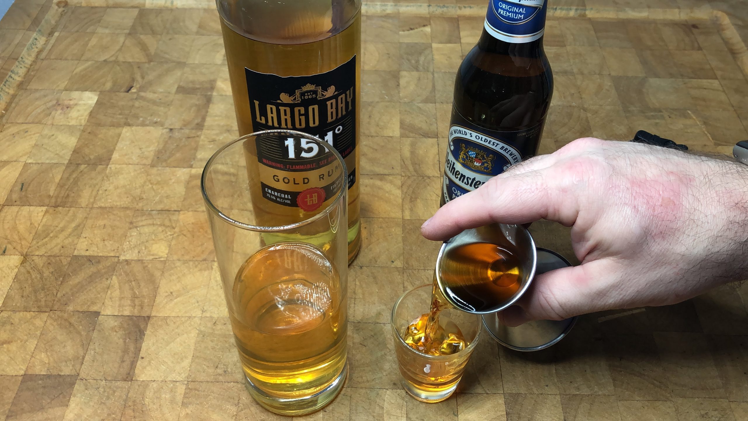 Pouring amaretto from a jigger into a shot glass.
