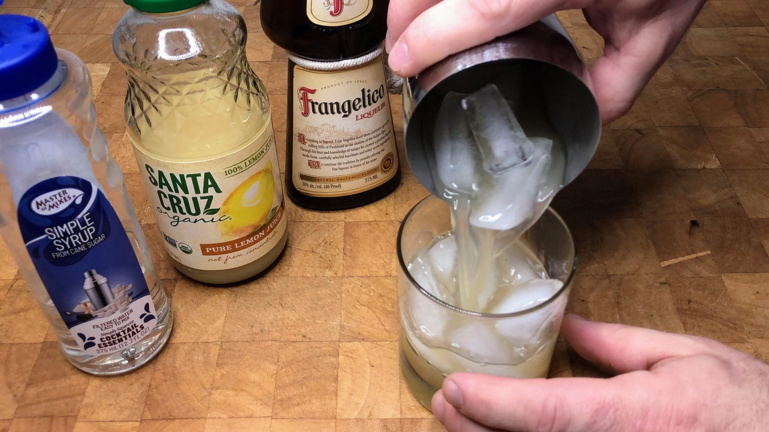 Tossing frangelico sour from cocktail shaker into rocks glass.