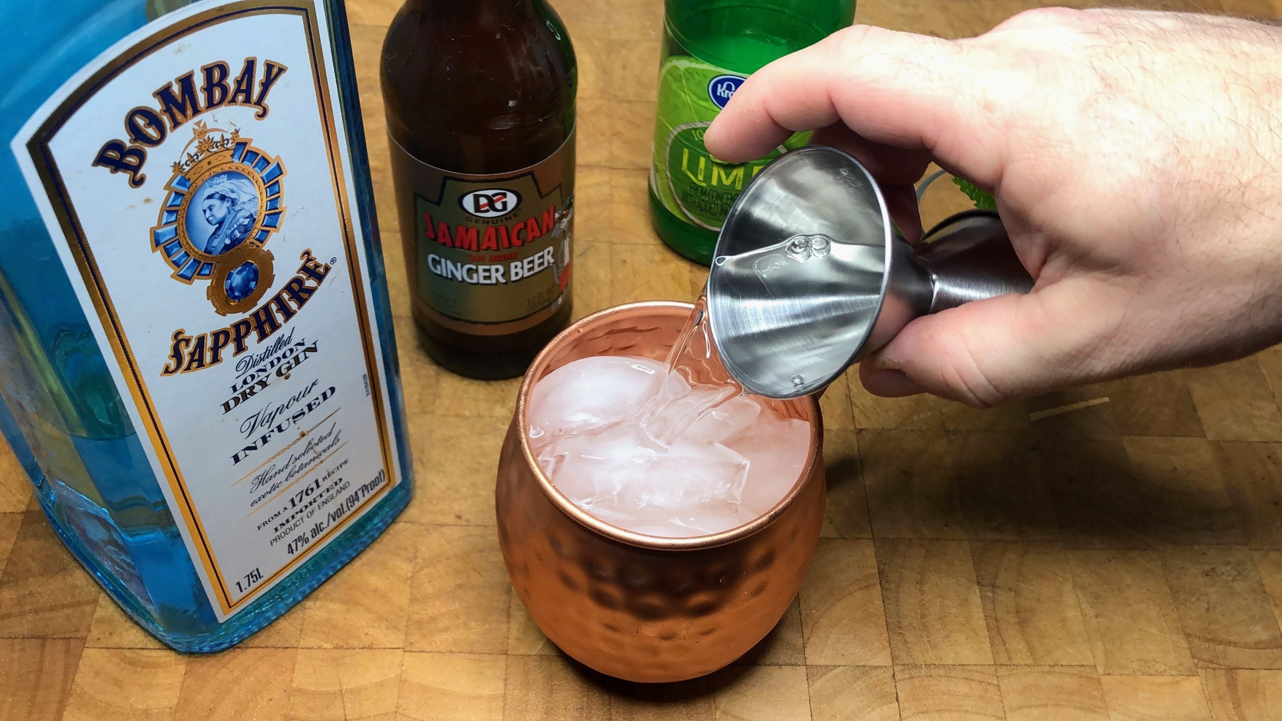 pouring gin into a copper mug