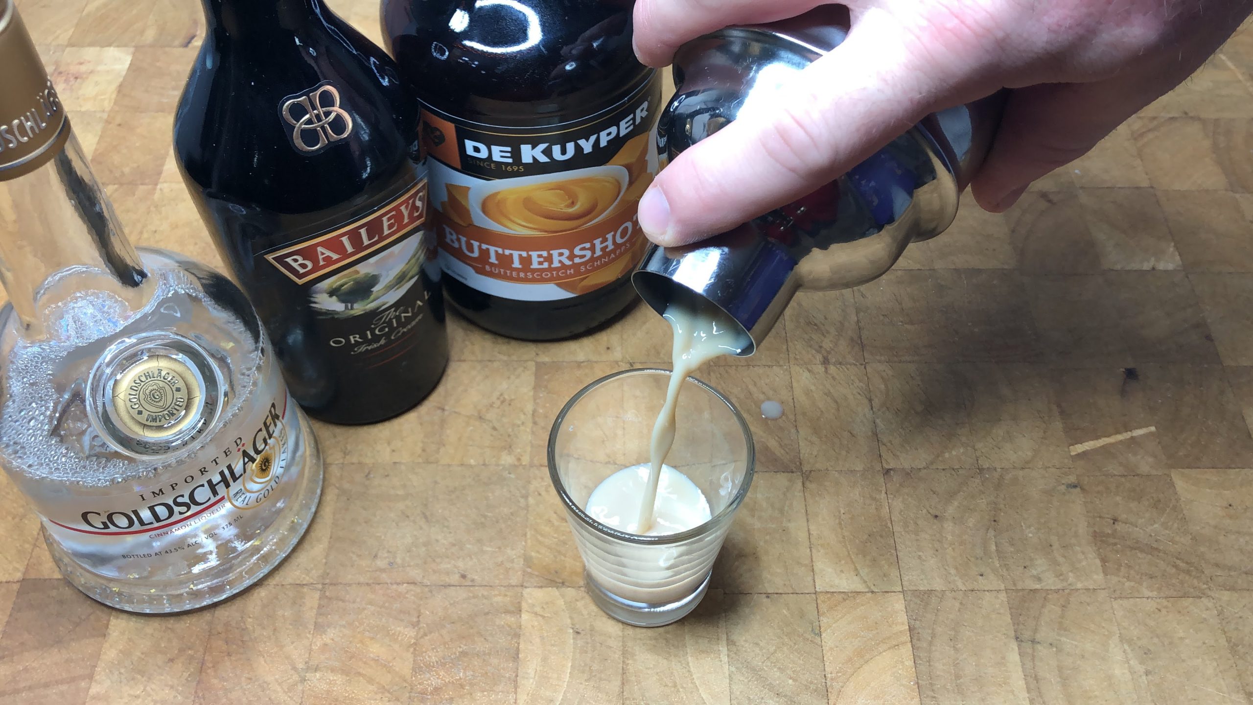 Pouring golden butterball shot from shaker into a shot glass.